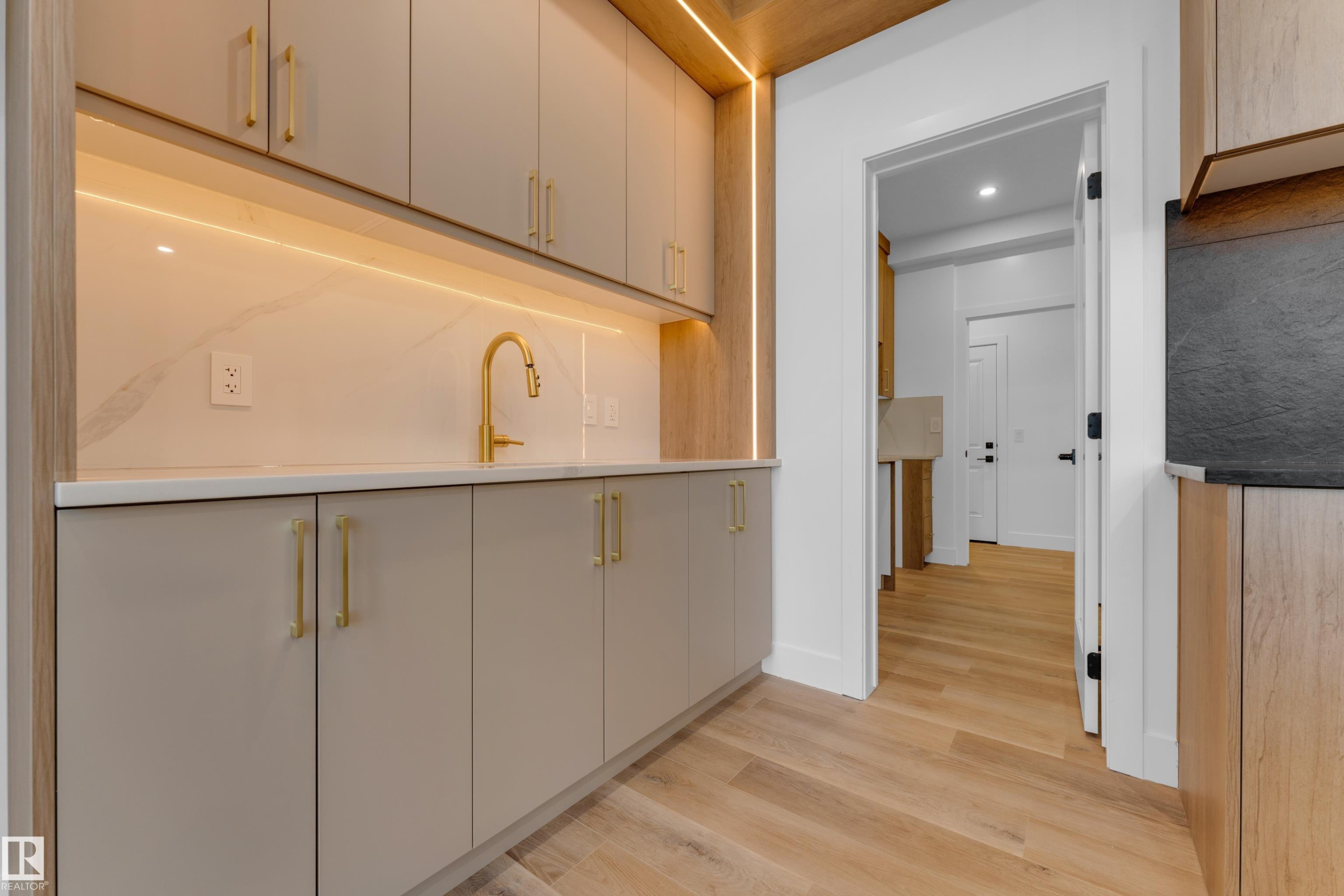 Wet bar featuring light-toned cabinetry, light wood-finish flooring, a gold-finish faucet, and integrated lighting - 236 Linden Loop, Leduc, AB