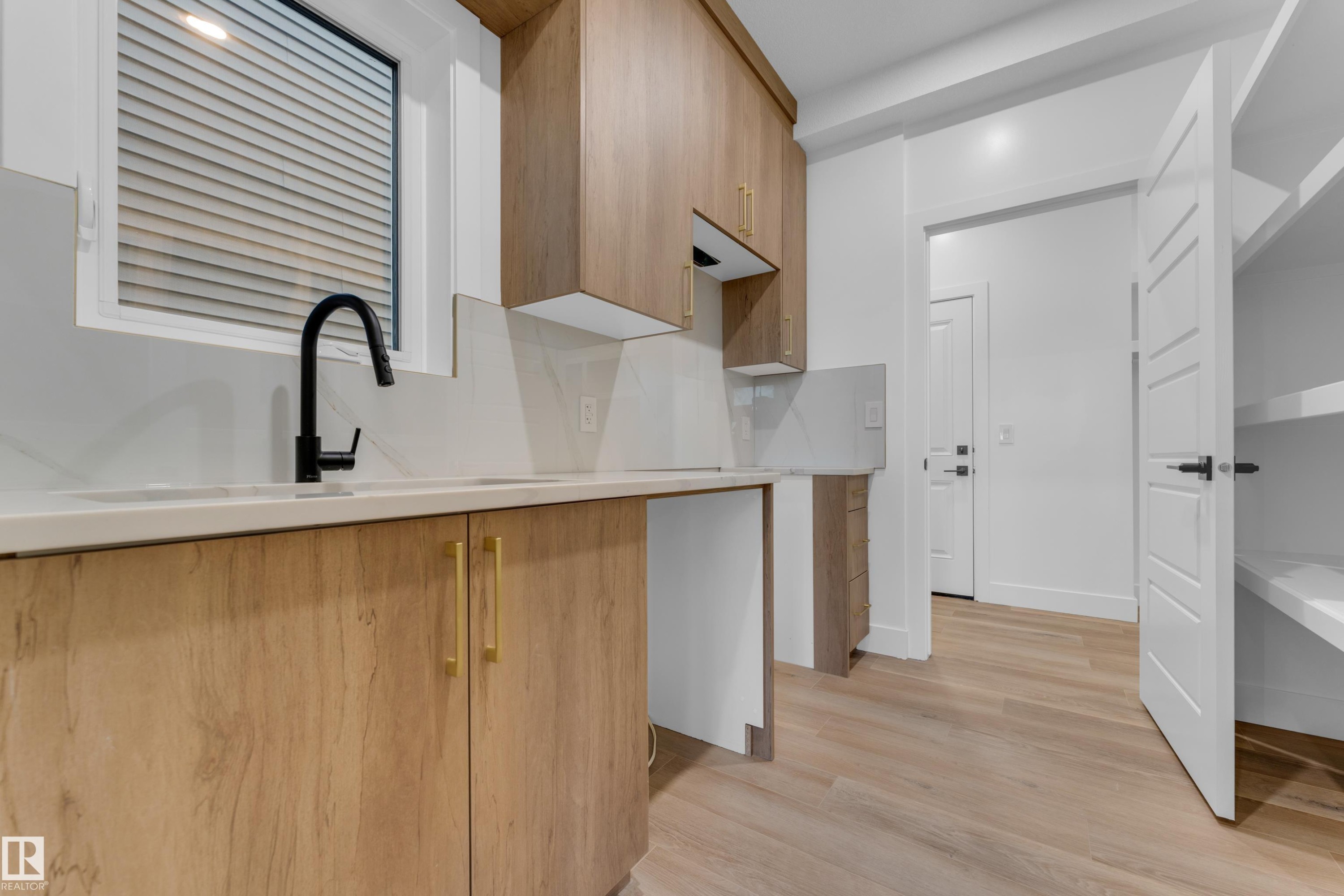 Wood-finish cabinetry with brass hardware, undermount sink, and a matte black faucet - 236 Linden Loop, Leduc, AB