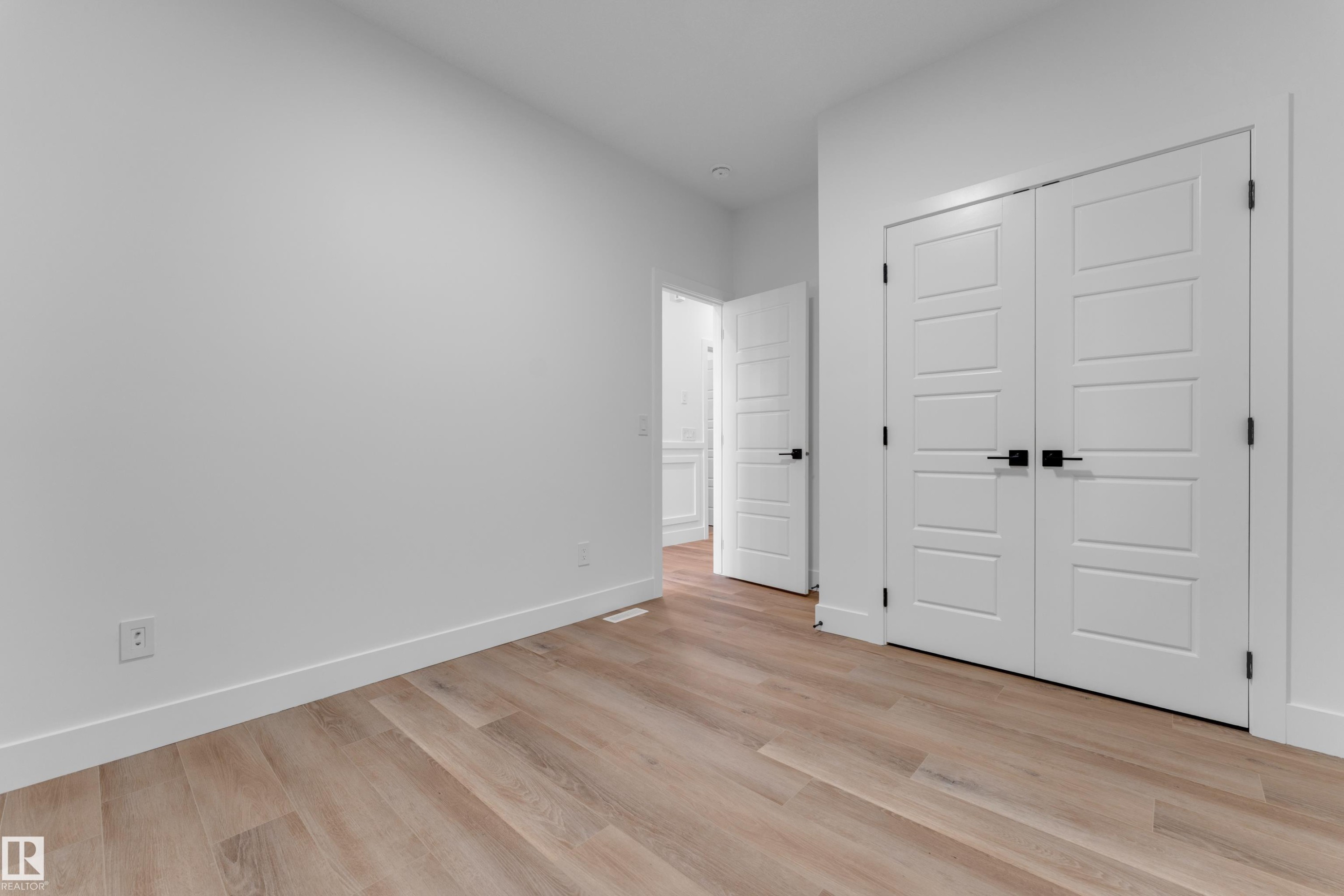 Light wood-finish flooring with white baseboards, and white walls - 236 Linden Loop, Leduc, AB