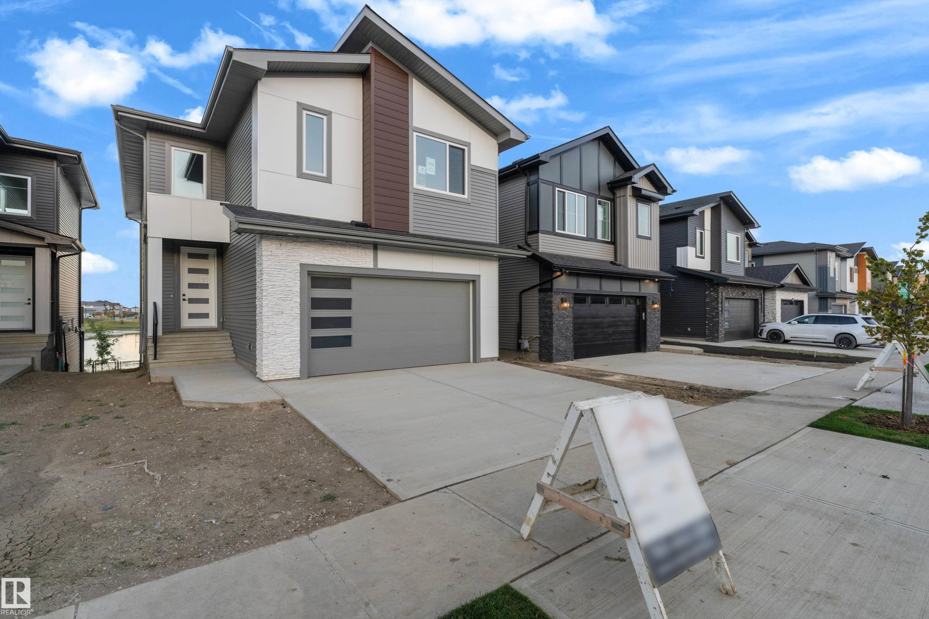 Contemporary exterior with mixed material facade, integrated garage, concrete driveway, and front entry with modern door - 236 Linden Loop, Leduc, AB