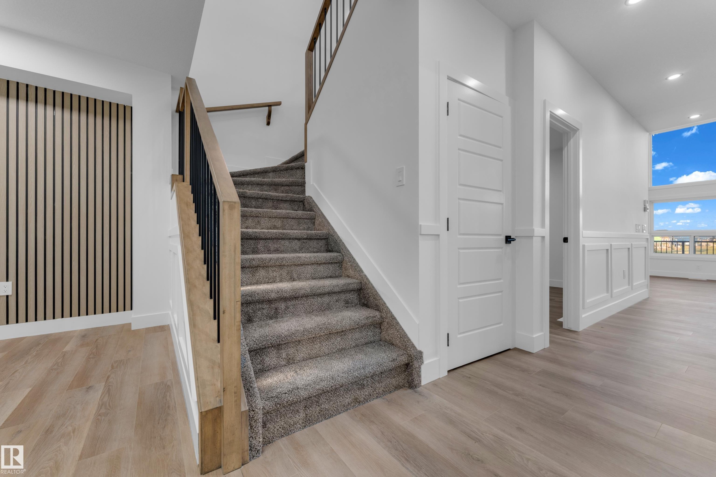 Staircase featuring carpeted treads and wood handrails with black metal balusters - 236 Linden Loop, Leduc, AB