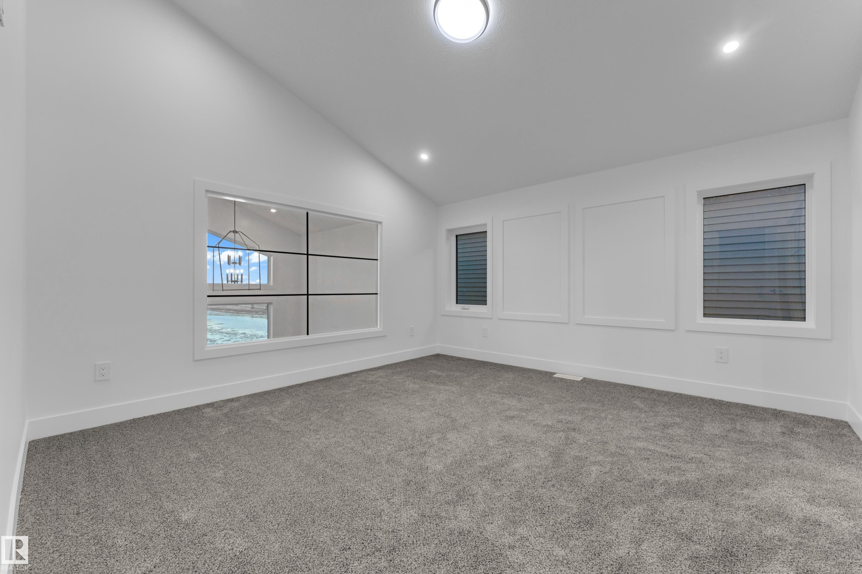 Vaulted ceiling, two recessed lights, flush-mount ceiling light, paneled wall detailing, and grey carpeting - 236 Linden Loop, Leduc, AB