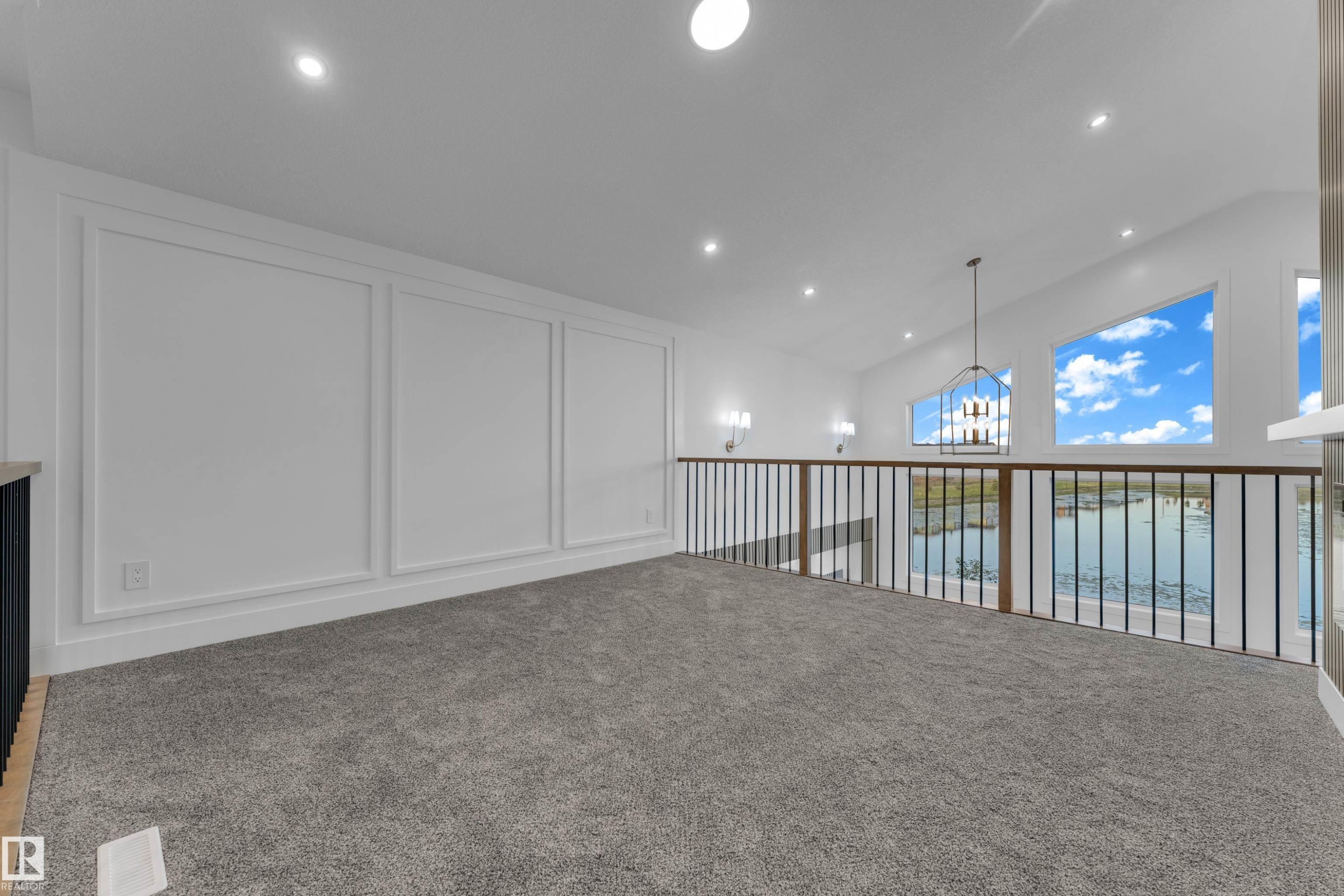Loft space featuring a vaulted ceiling with recessed lighting, carpet flooring, decorative wall molding, and a metal and wood-finish railing - 236 Linden Loop, Leduc, AB