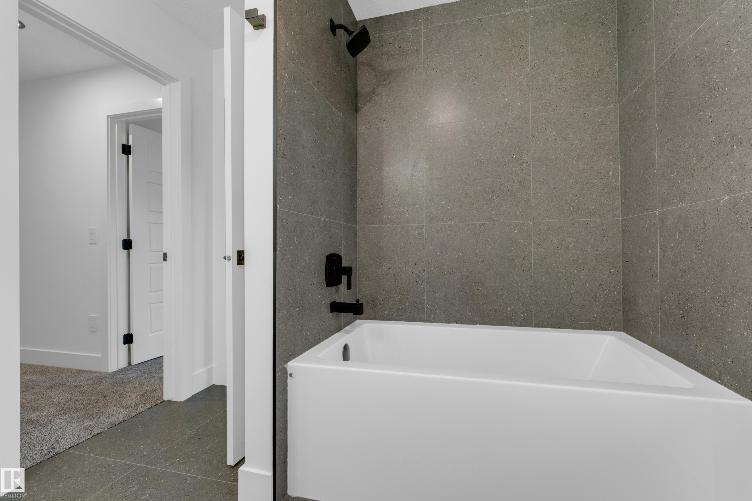 White bathtub with dark gray shower tile, matte black shower fixtures, and gray floor tile - 236 Linden Loop, Leduc, AB