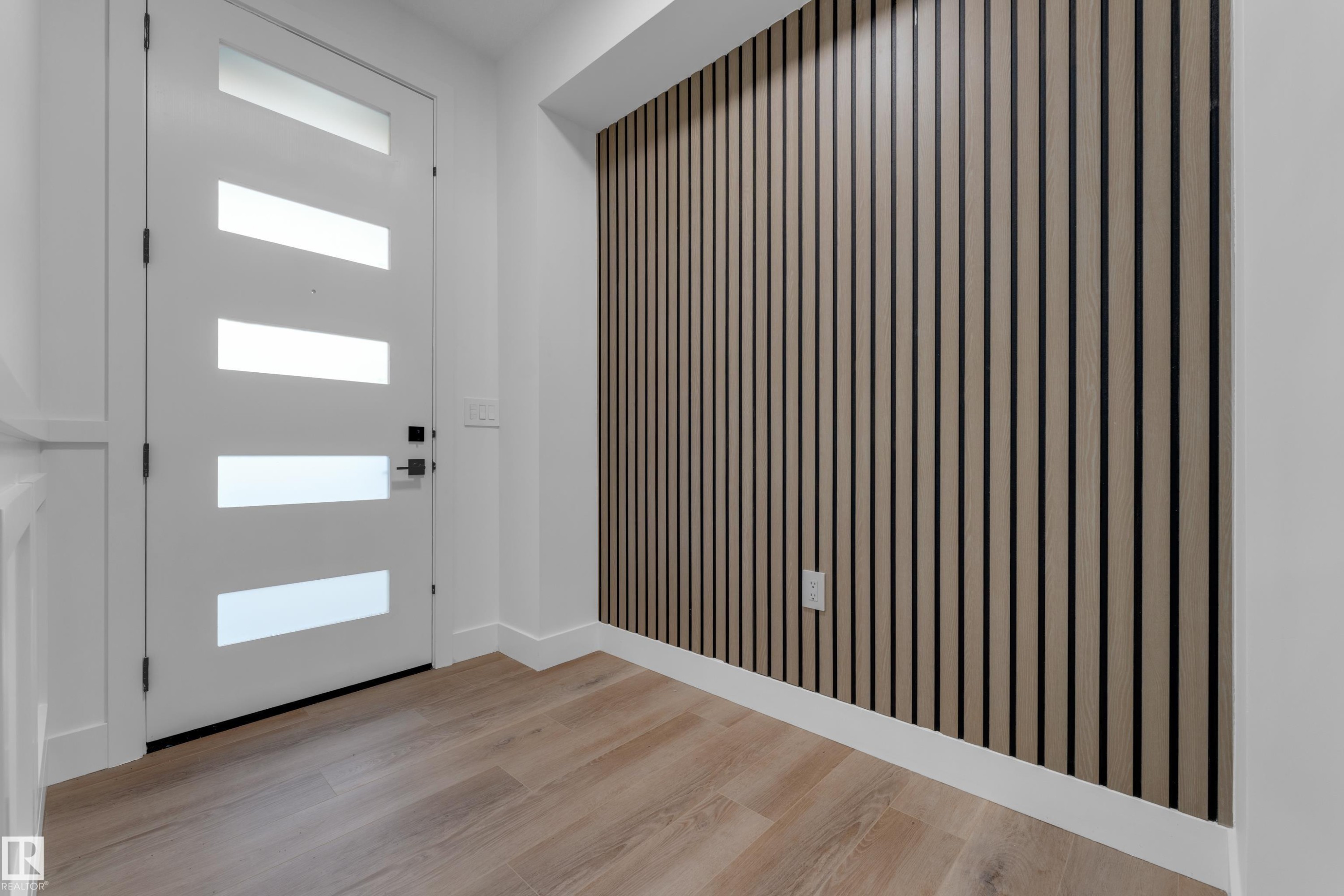 Modern white entry door with frosted glass inserts, wood-finish flooring, and a textured accent wall - 236 Linden Loop, Leduc, AB