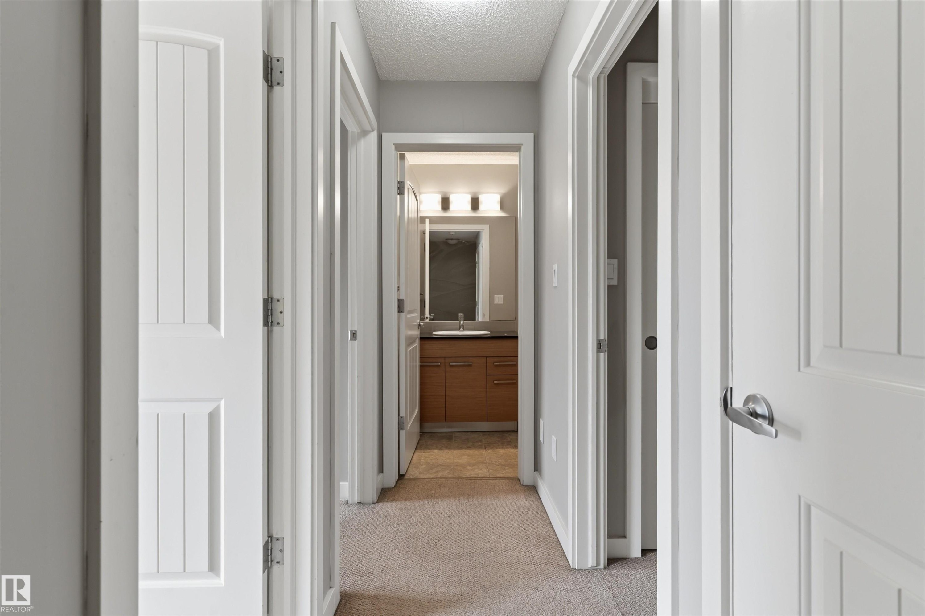 Hallway featuring carpeted flooring and multiple white paneled doors with chrome hardware - #62 675 Watt Bv Sw, Edmonton, AB
