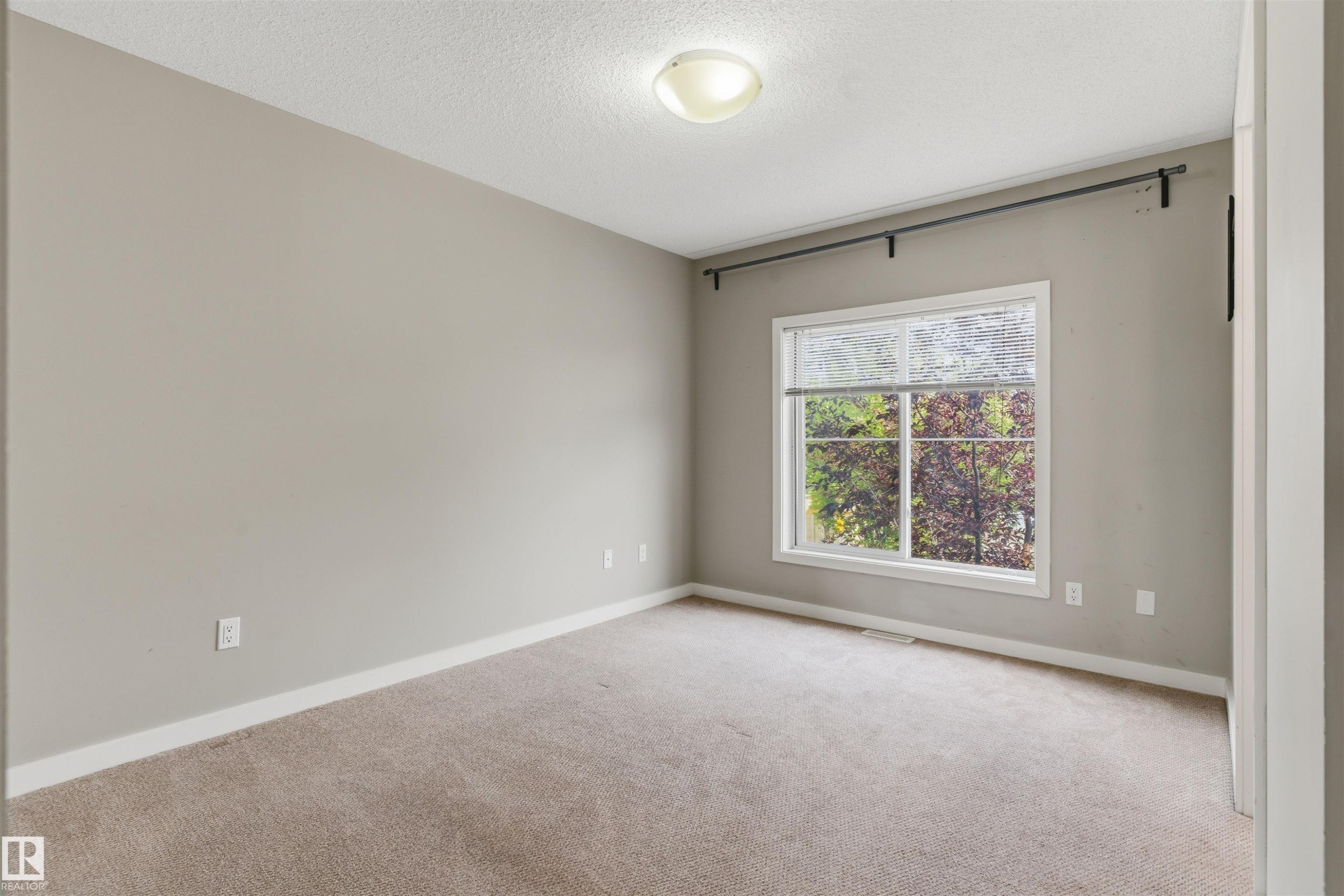 Neutral-toned walls, carpeting, white trim, and a window with a curtain rod - #62 675 Watt Bv Sw, Edmonton, AB