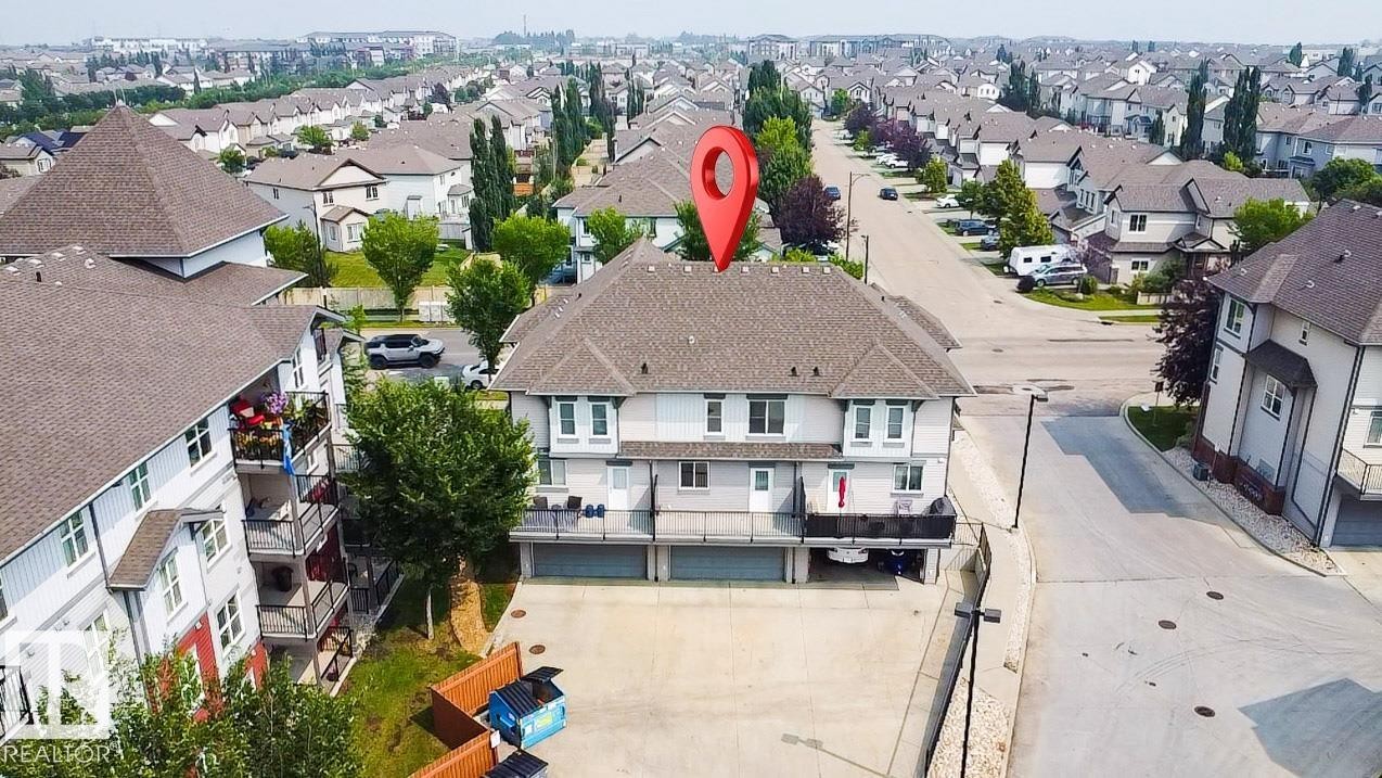 Multi-level residential building featuring private balconies, individual garages, and a paved parking area - #62 675 Watt Bv Sw, Edmonton, AB