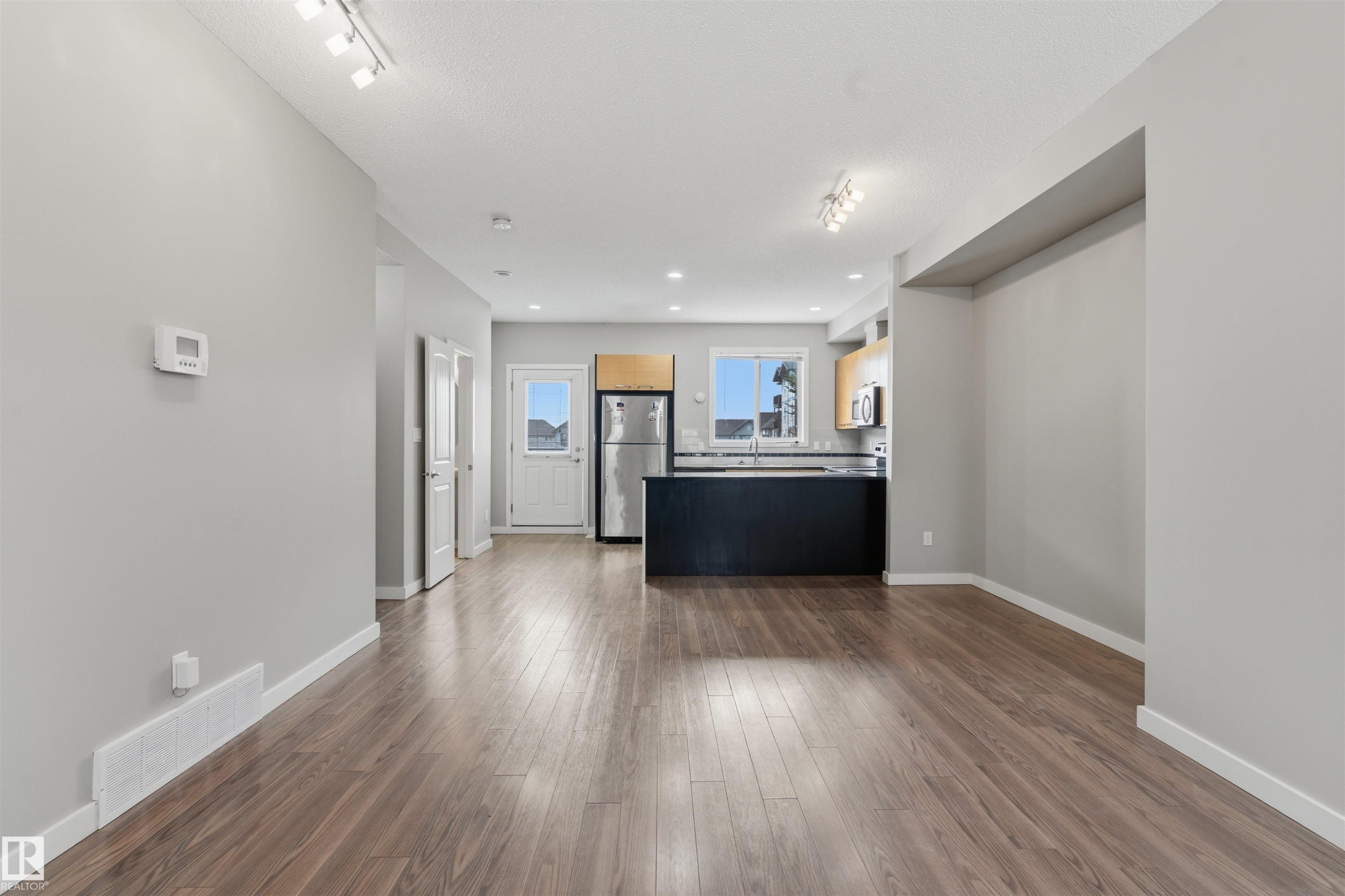 Open-concept living space with wood-finish flooring, recessed lighting, and track lighting - #62 675 Watt Bv Sw, Edmonton, AB