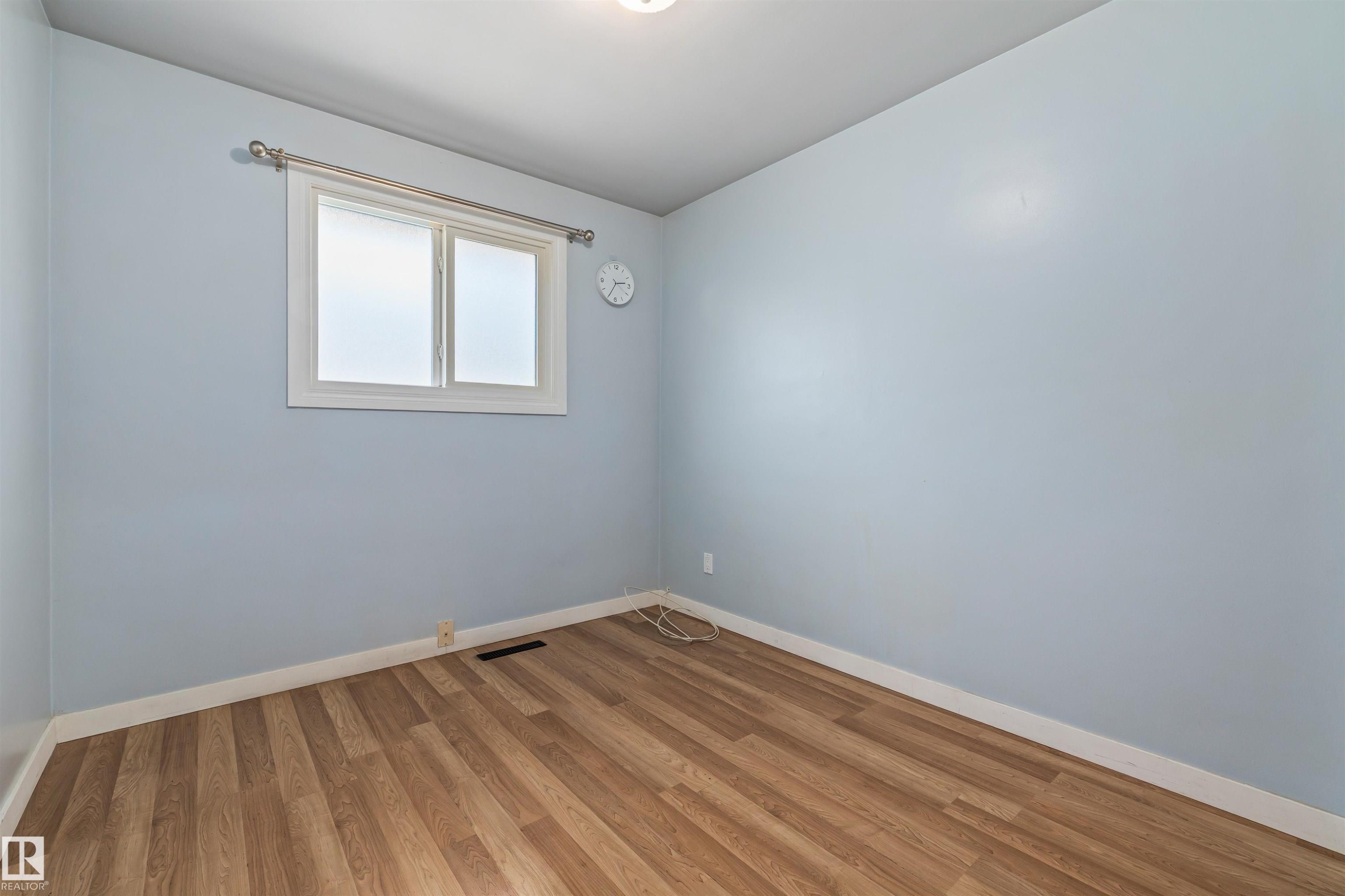 Room featuring wood-finish flooring, light blue walls, and white baseboards - 13320 123 Street Nw, Edmonton, AB - Indoor Photo Showing Other Room