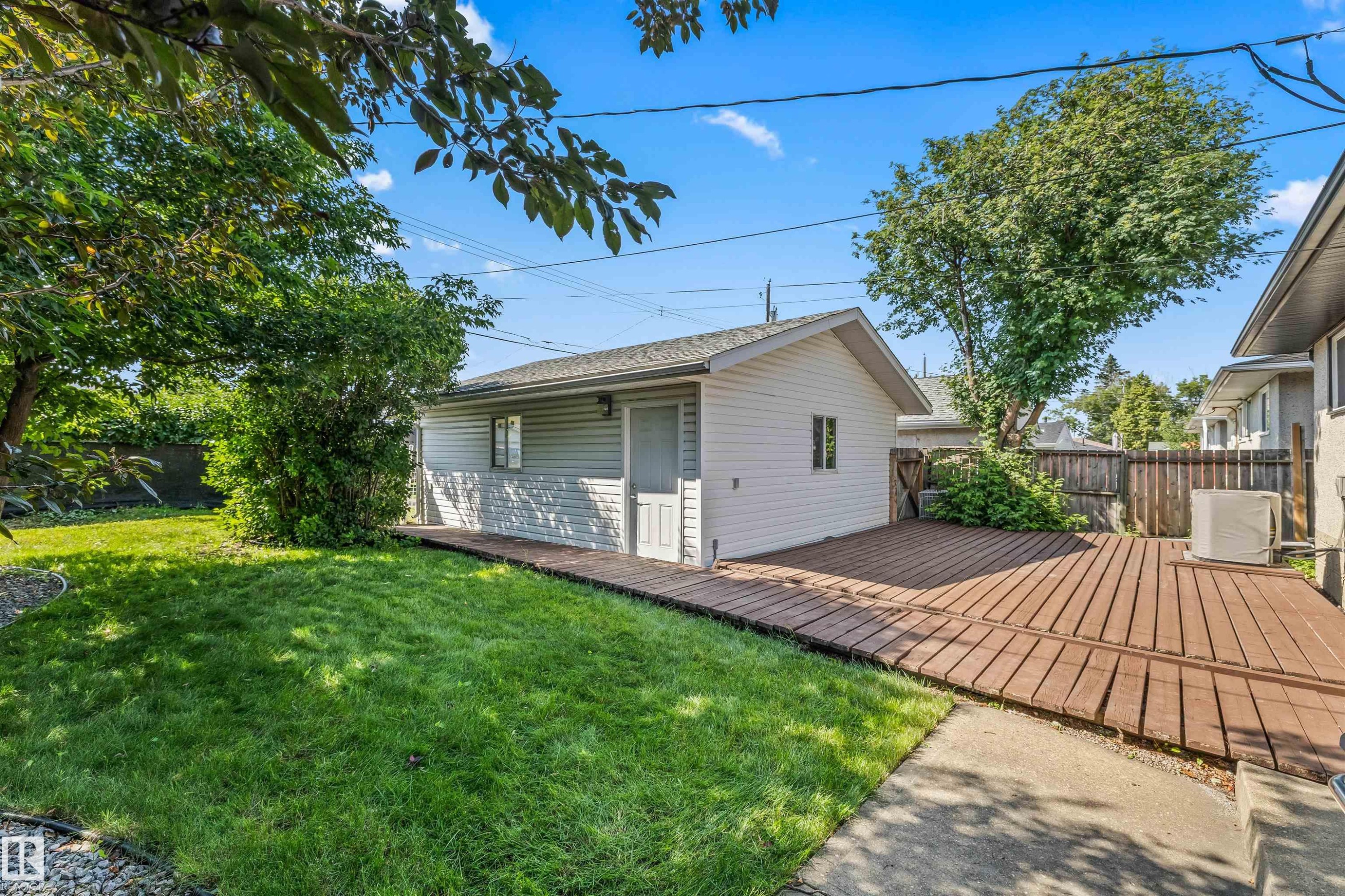 Detached garage with siding exterior, wood-plank deck, and a fenced yard with mature trees and a manicured lawn - 13320 123 Street Nw, Edmonton, AB - Outdoor With Deck Patio Veranda With Exterior