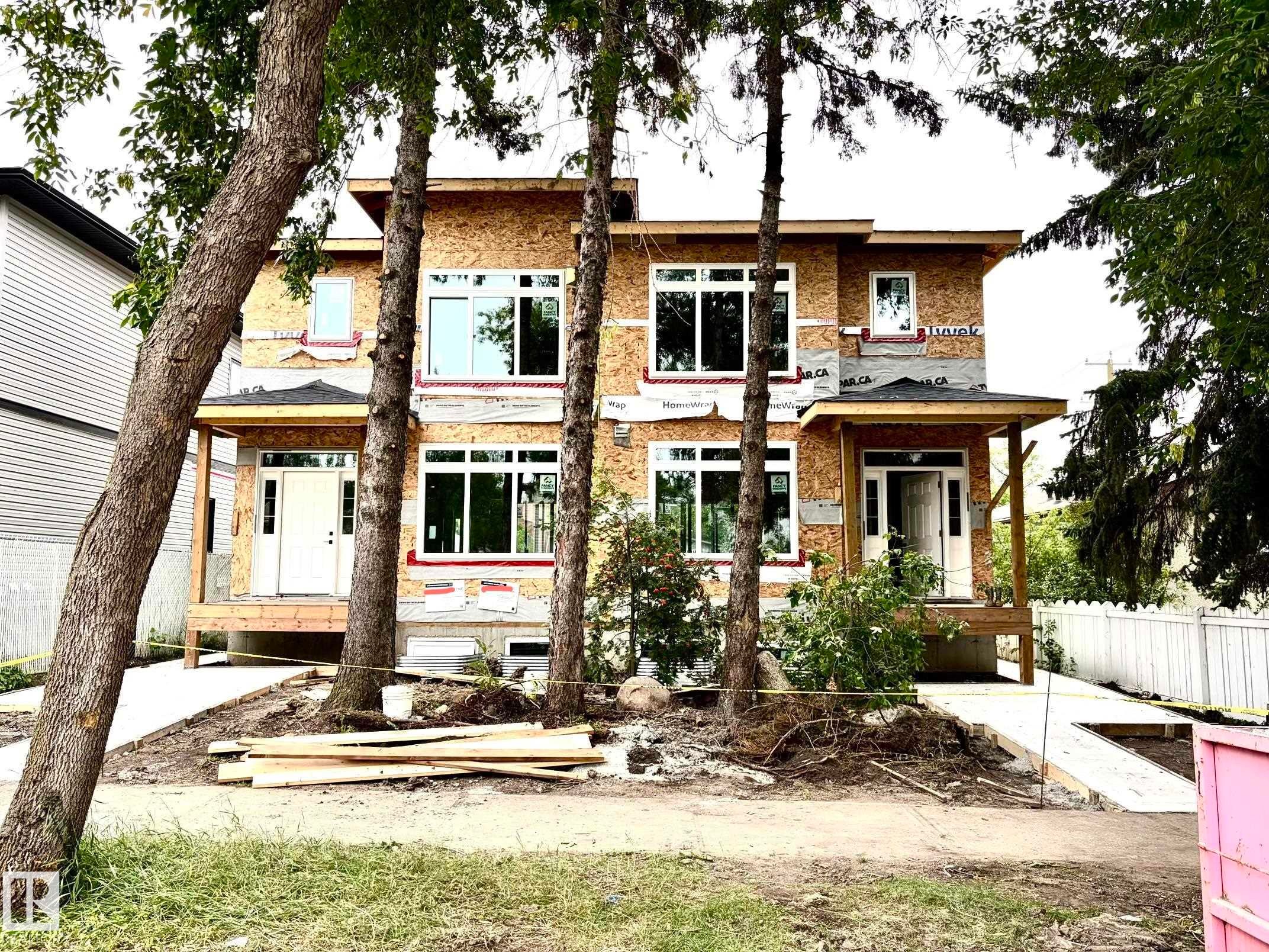 New construction duplex featuring multiple windows, covered entryways, and concrete pathways - 12909 69 Street Nw, Edmonton, AB