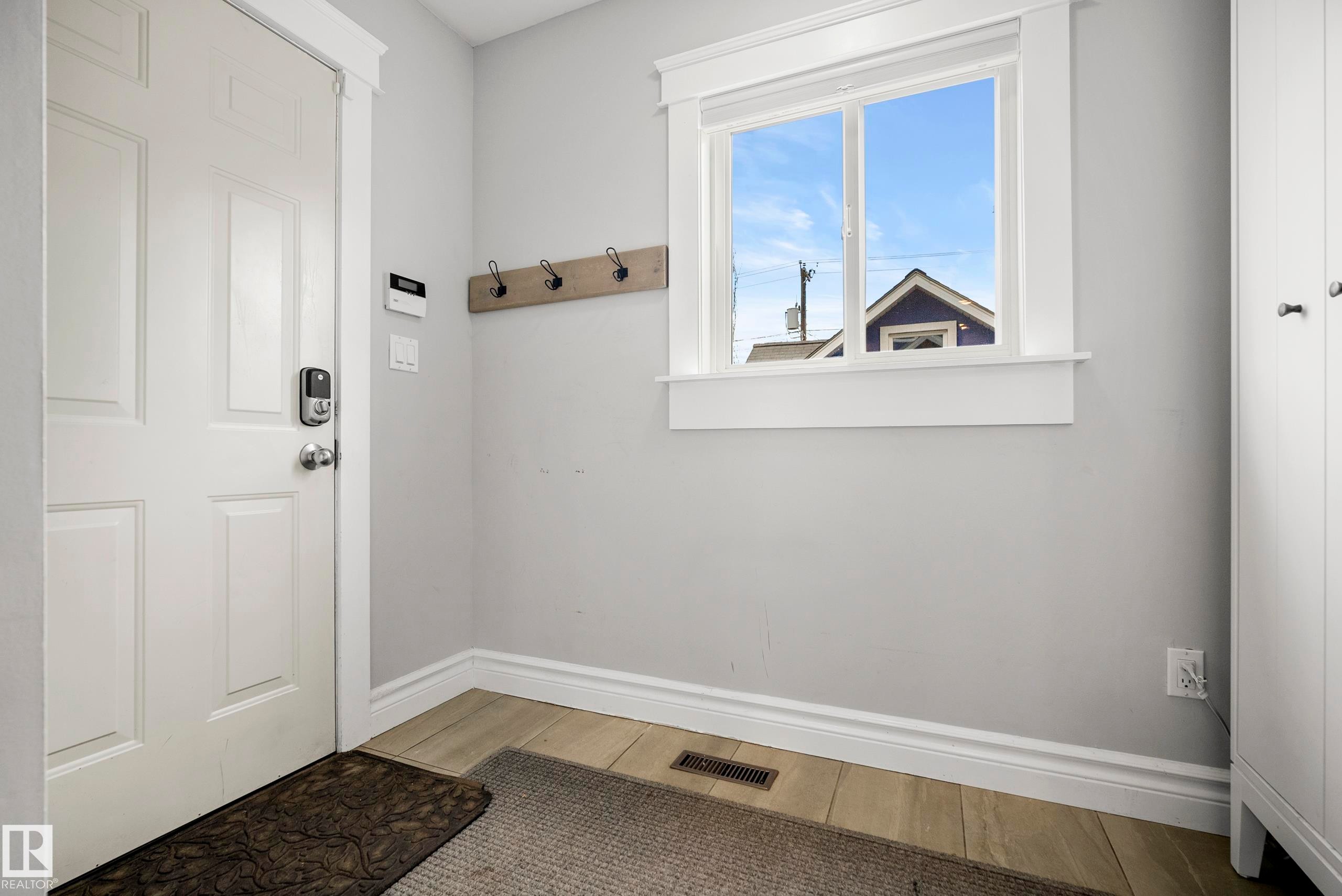 Entryway featuring a paneled door, wood-finish flooring, and a built-in coat rack - 11006 64 Avenue Nw, Edmonton, AB