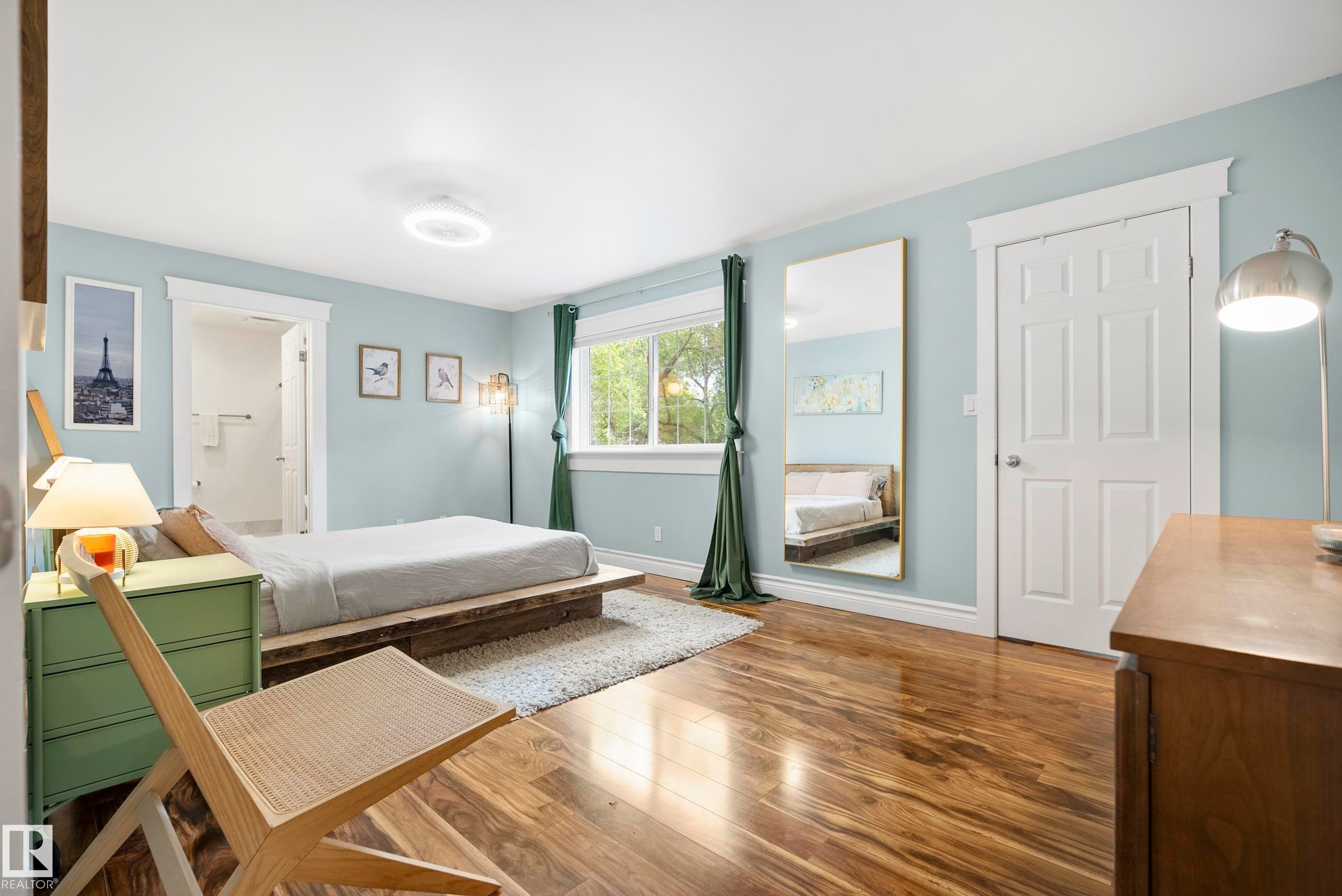 Hardwood flooring, light blue wall paint, white trim, recessed ceiling light, and a window with green drapes - 11006 64 Avenue Nw, Edmonton, AB