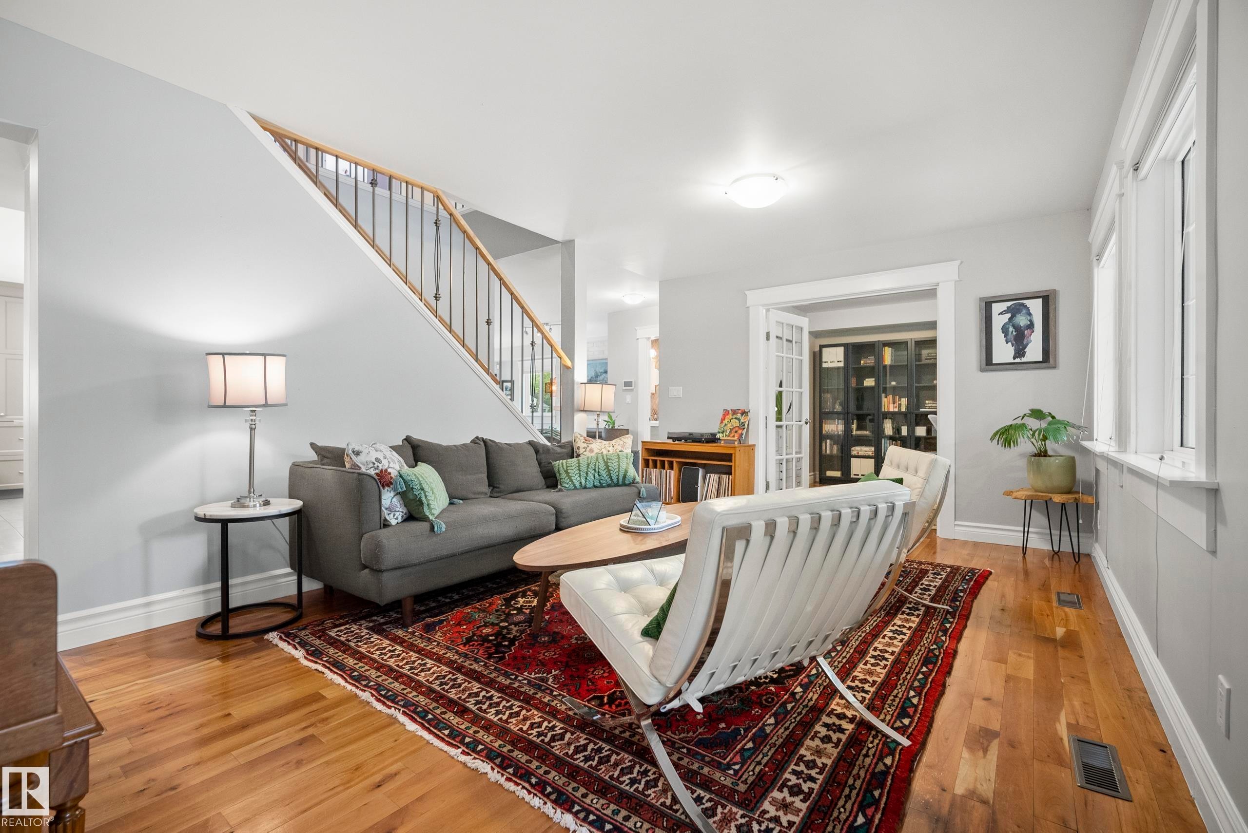 Hardwood flooring, white trim, staircase with wood handrail and black balusters, recessed lighting, and French doors - 11006 64 Avenue Nw, Edmonton, AB