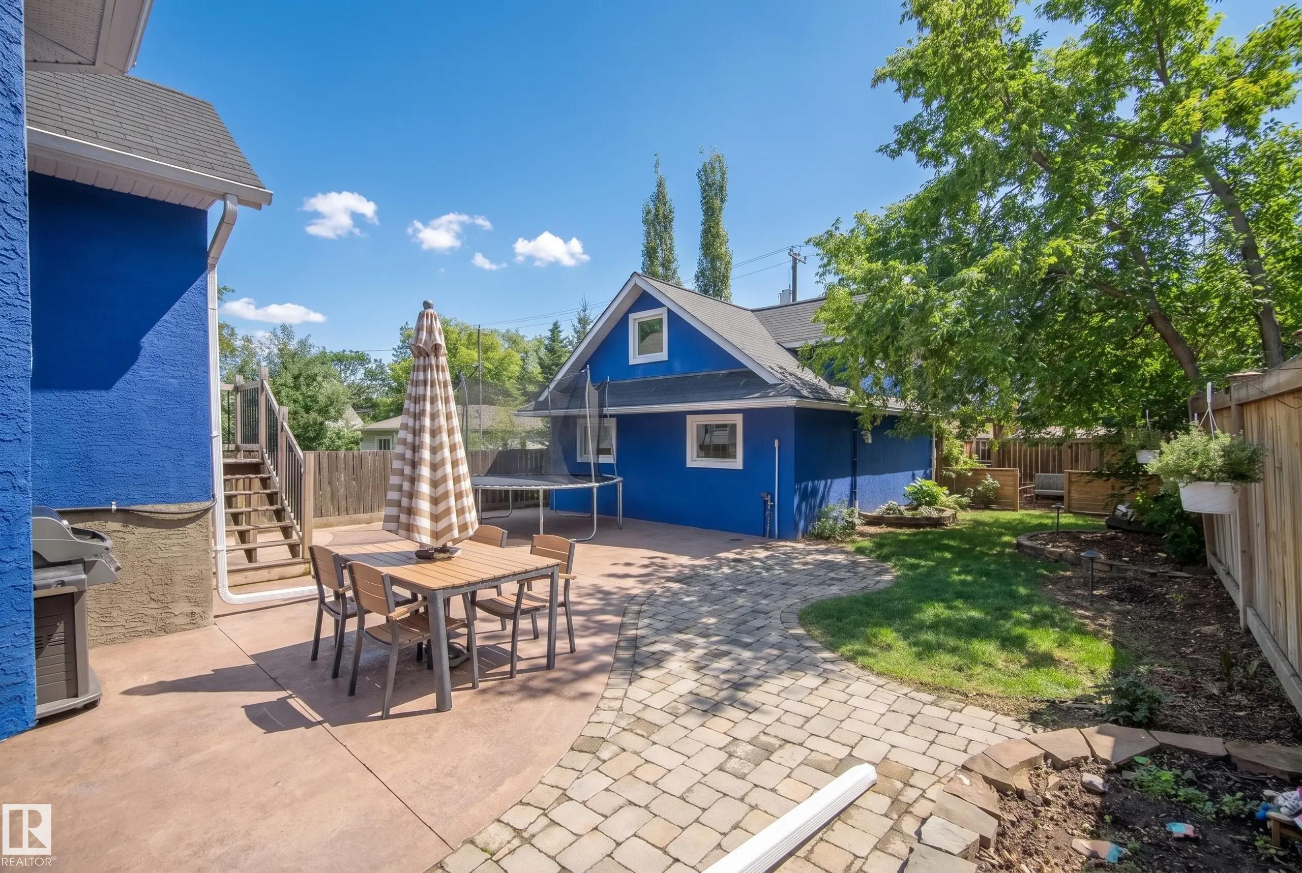 Expansive backyard featuring a stamped concrete patio, paver patio, detached auxiliary structure, and wood privacy fencing - 11006 64 Avenue Nw, Edmonton, AB