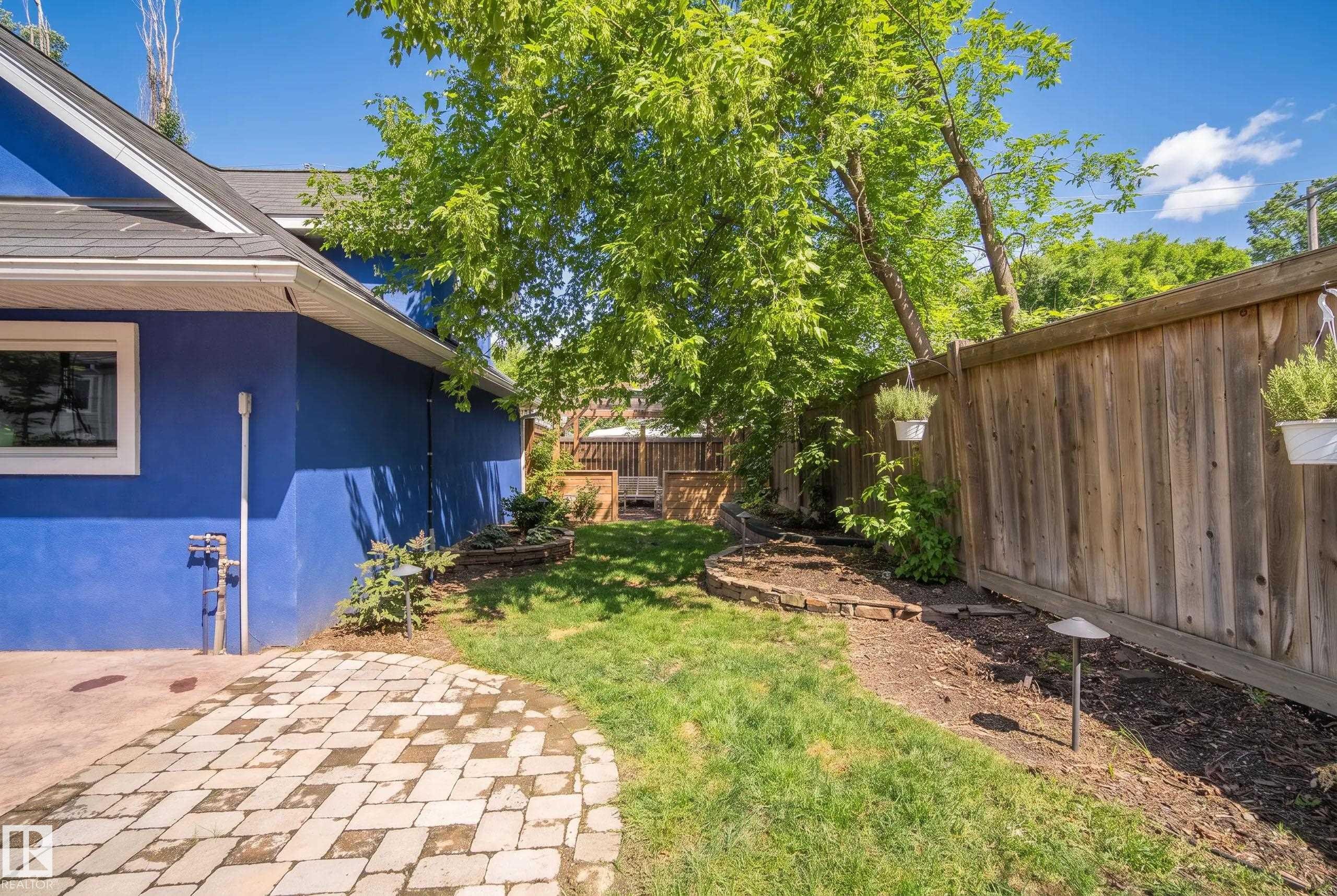 Exterior siding with a window, paver patio, wood fence, and landscaped garden beds - 11006 64 Avenue Nw, Edmonton, AB