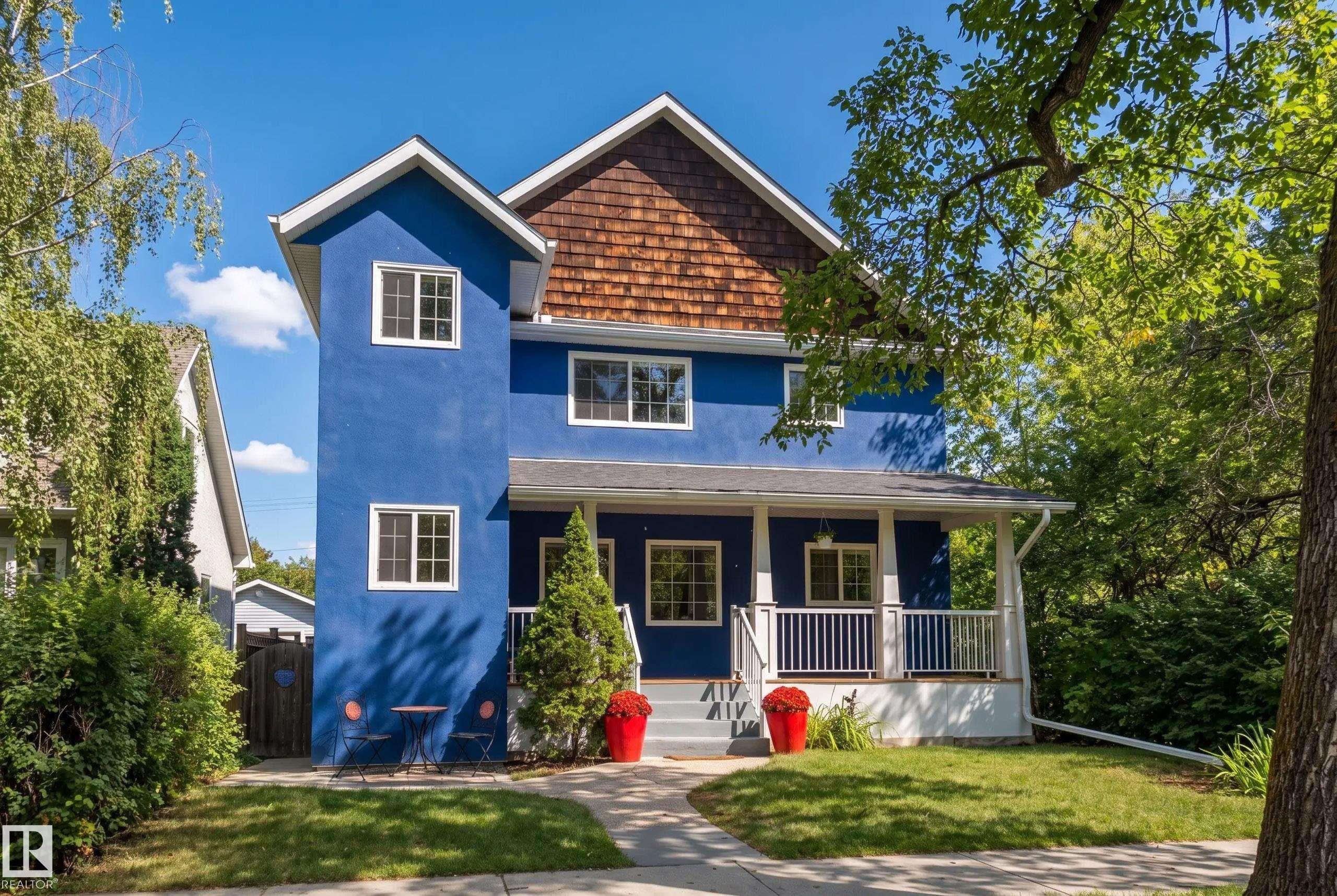 Striking blue Colonial-style home featuring a gabled roofline with cedar shake accents, white trim detailing, and multi-pane windows - 11006 64 Avenue Nw, Edmonton, AB