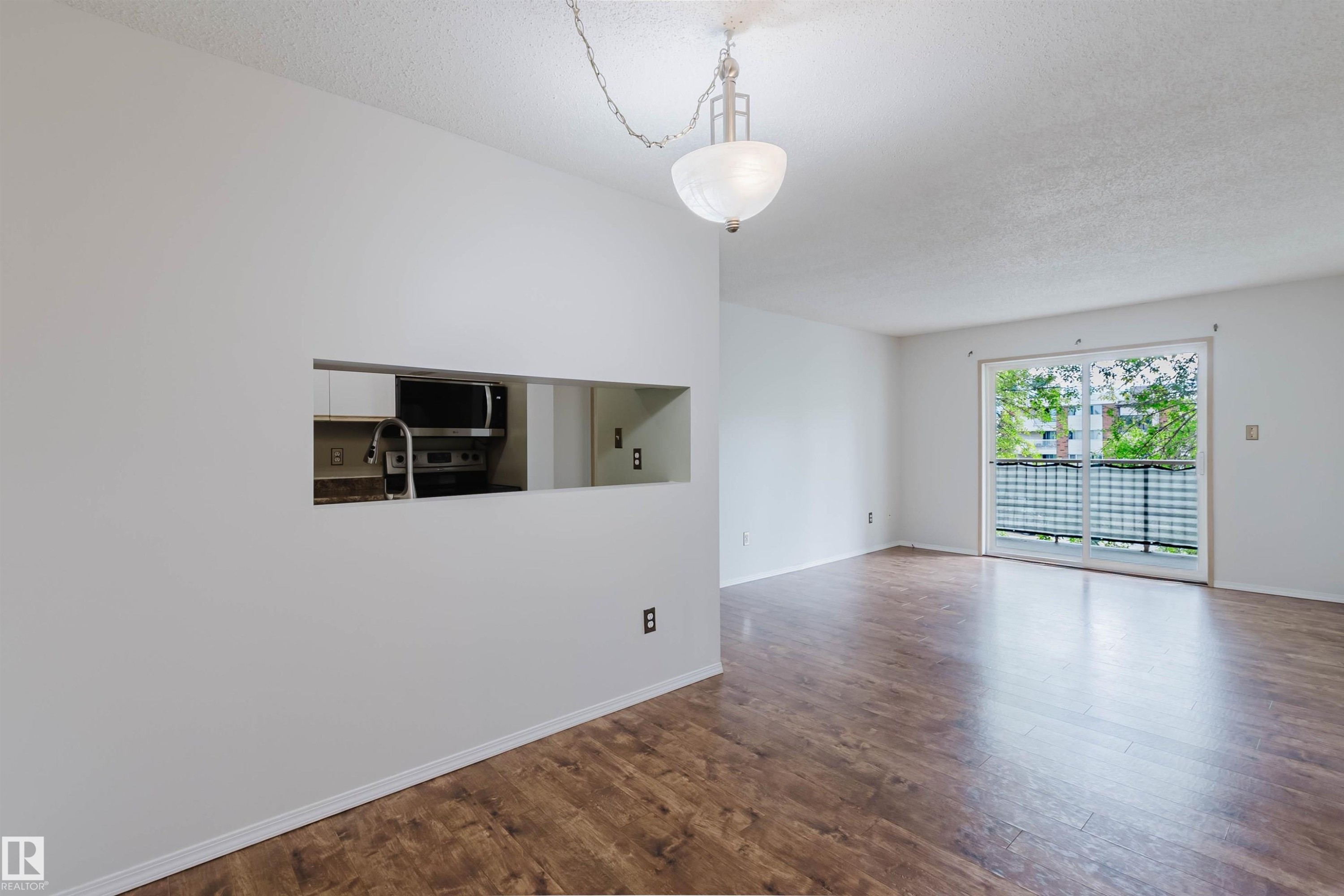 Wood-finish flooring throughout, with a pass-through opening to the kitchen - #316 17109 67 Av Nw, Edmonton, AB