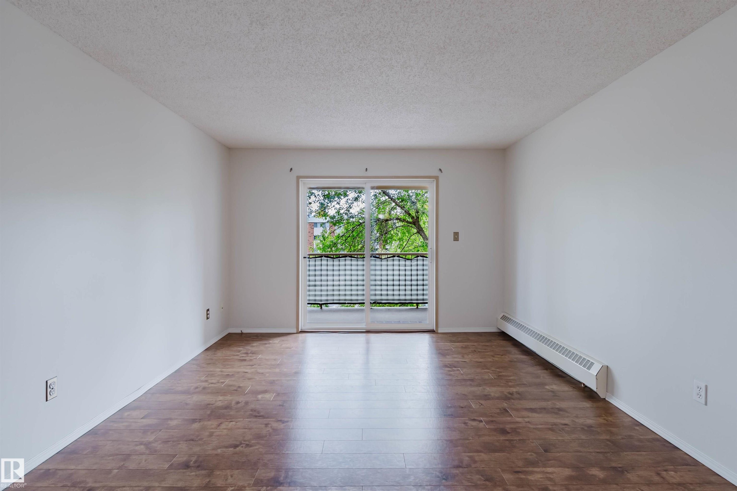 Wood-finish flooring, white walls, and a sliding glass door with a privacy screen - #316 17109 67 Av Nw, Edmonton, AB