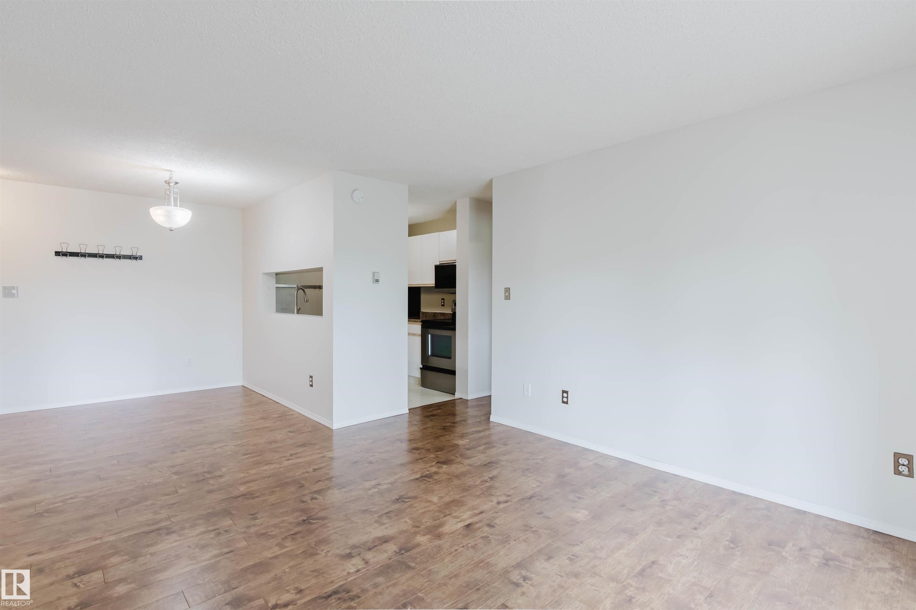 Hardwood-finish flooring, white walls, semi-flush ceiling light fixture, kitchen pass-through, and built-in stainless steel appliances - #316 17109 67 Av Nw, Edmonton, AB