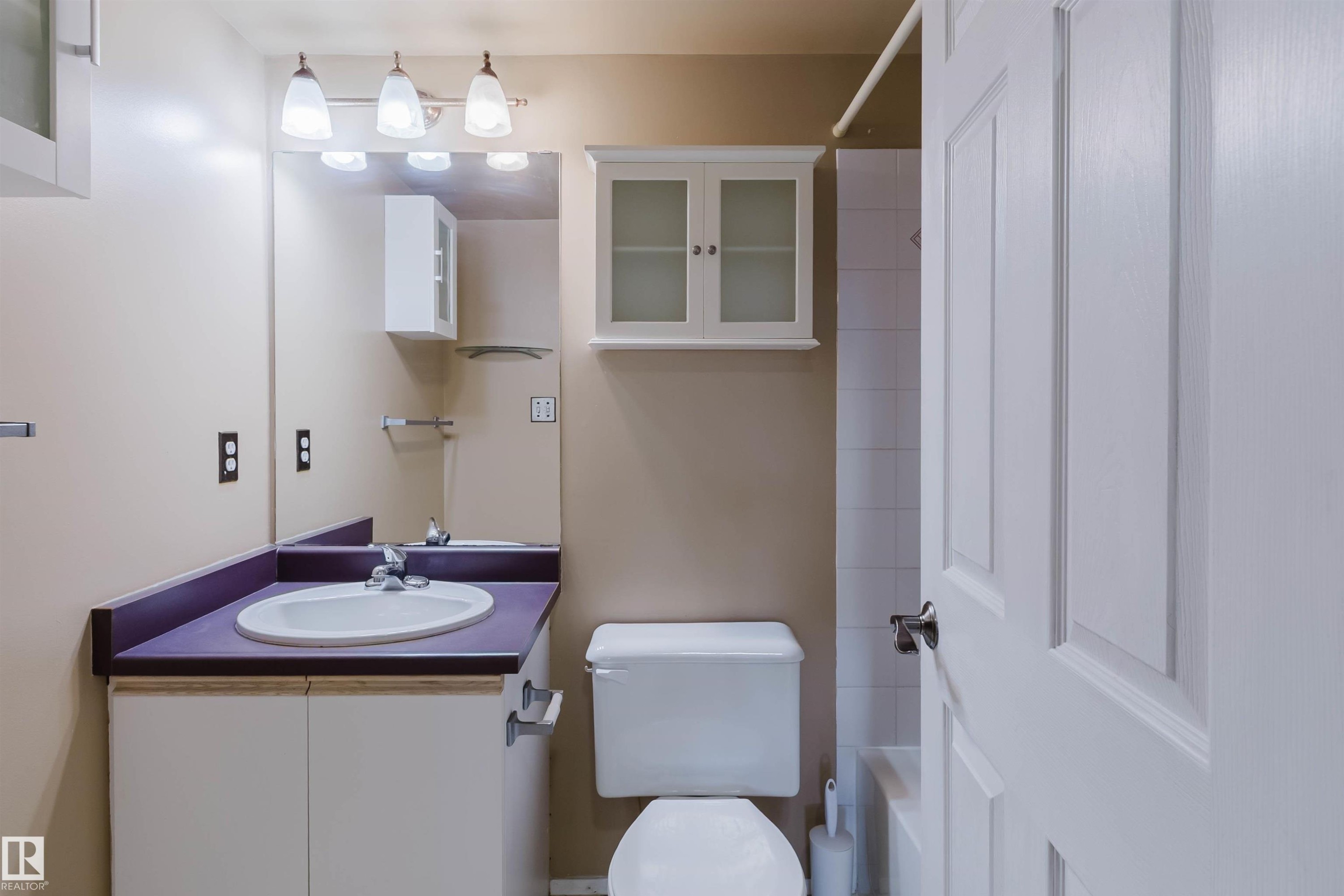Bathroom with a single vanity, undermount sink, wall-mounted mirror, and white panel door - #316 17109 67 Av Nw, Edmonton, AB