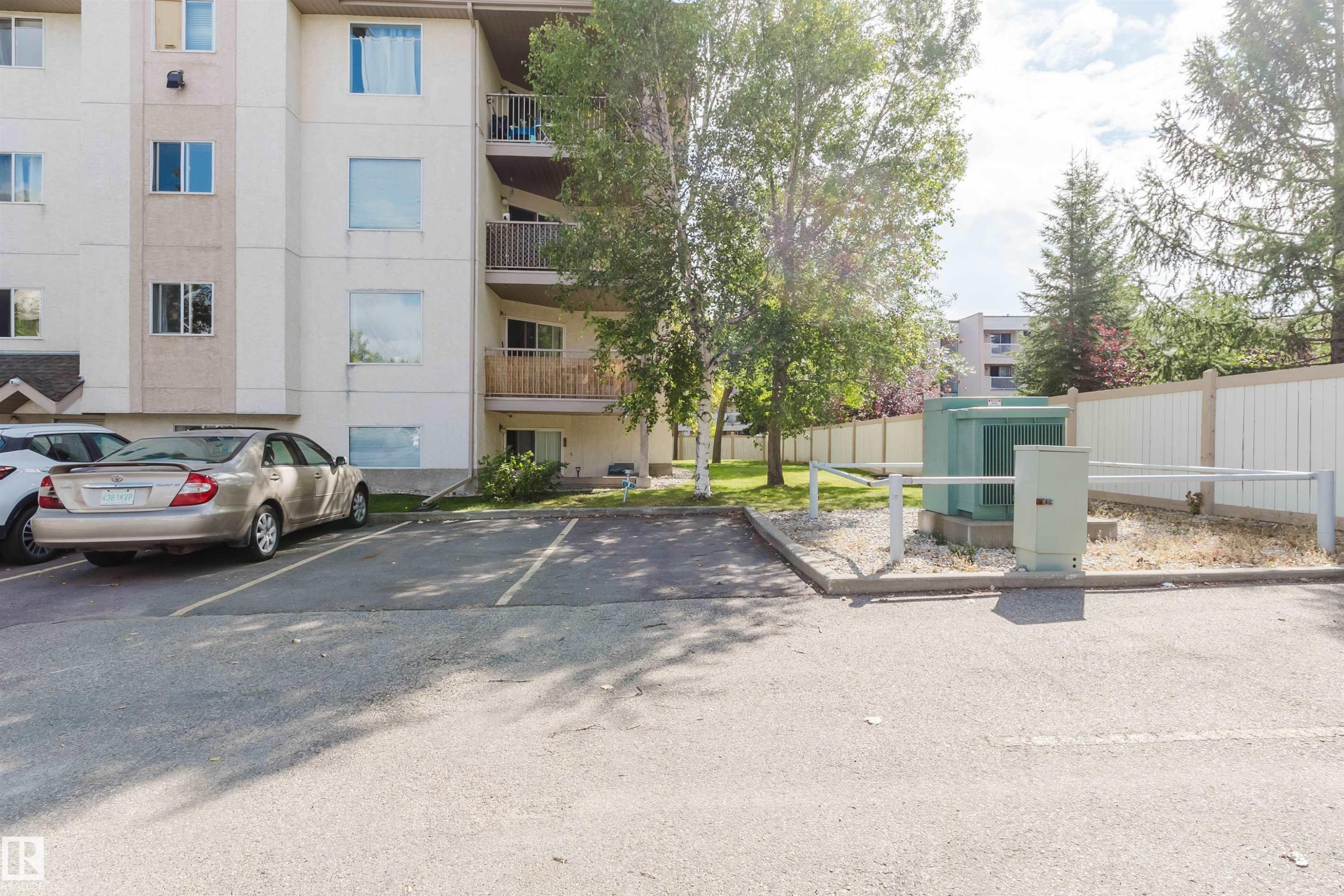 Paved parking lot featuring defined parking spaces, security gate, and perimeter fencing - #316 17109 67 Av Nw, Edmonton, AB