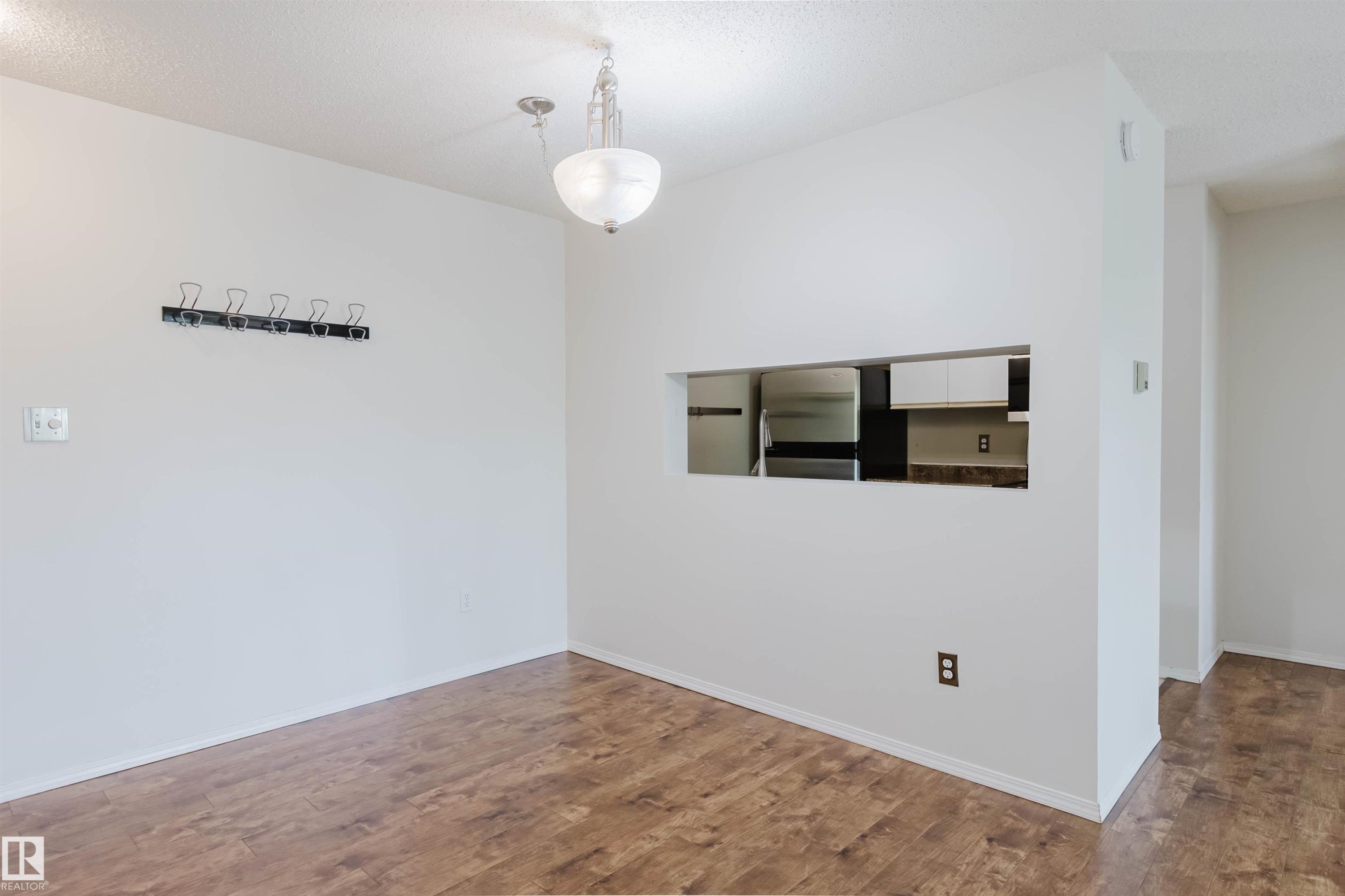 Wood-finish flooring throughout, with a built-in wall cutout to the kitchen - #316 17109 67 Av Nw, Edmonton, AB