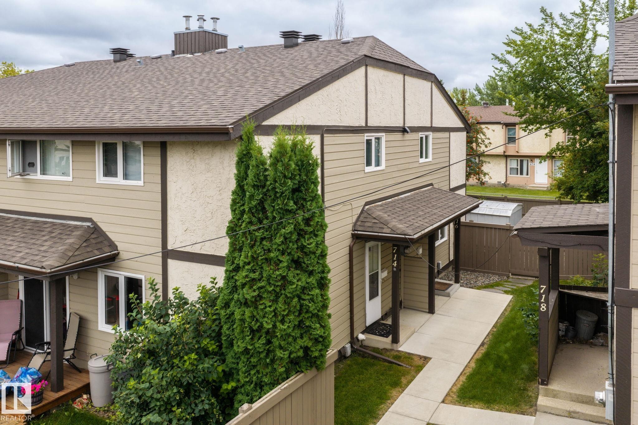 Two-story exterior with textured stucco and horizontal siding, covered front entry, asphalt shingle roof, and privacy fencing - 716 Clareview Rd Nw, Edmonton, AB