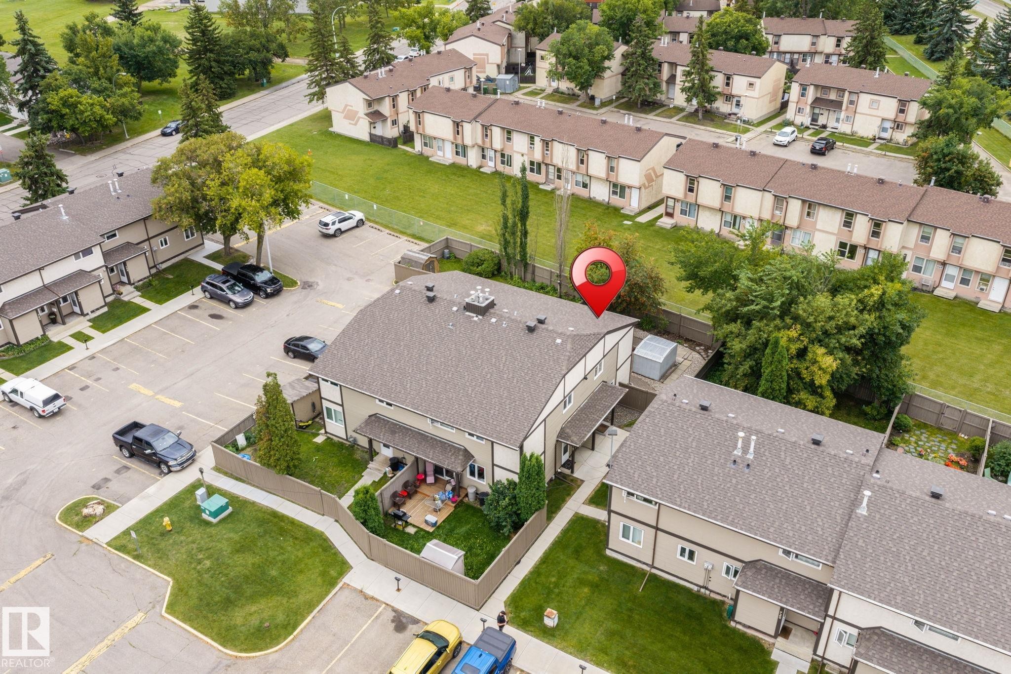 Townhome featuring a private fenced yard, a rear patio area, and an asphalt shingle roof - 716 Clareview Rd Nw, Edmonton, AB