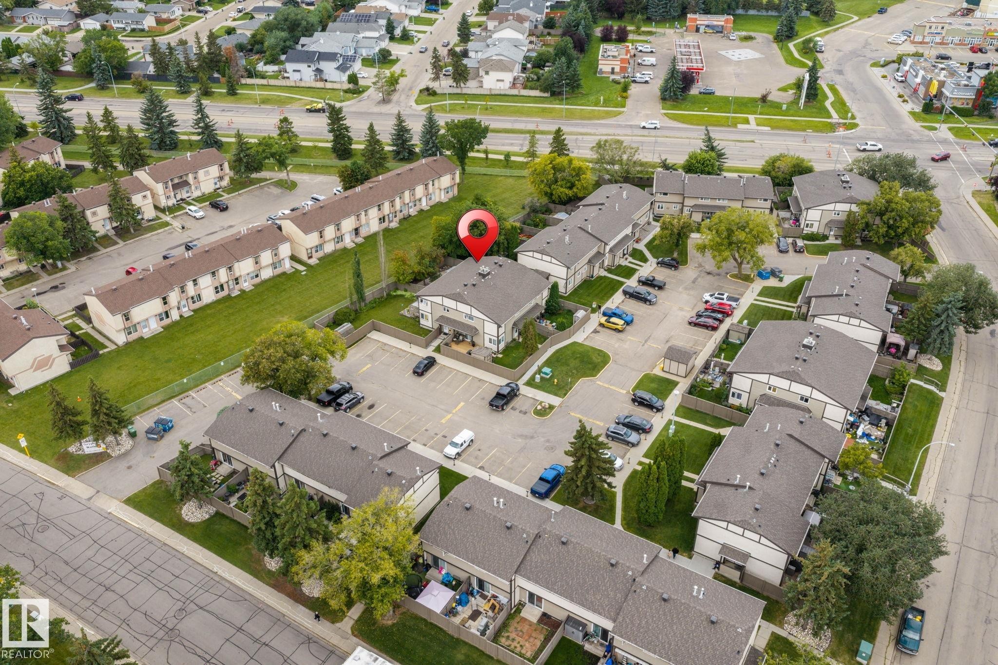 Multi-unit residential property featuring multiple structures, paved parking areas, and mature landscaping - 716 Clareview Rd Nw, Edmonton, AB
