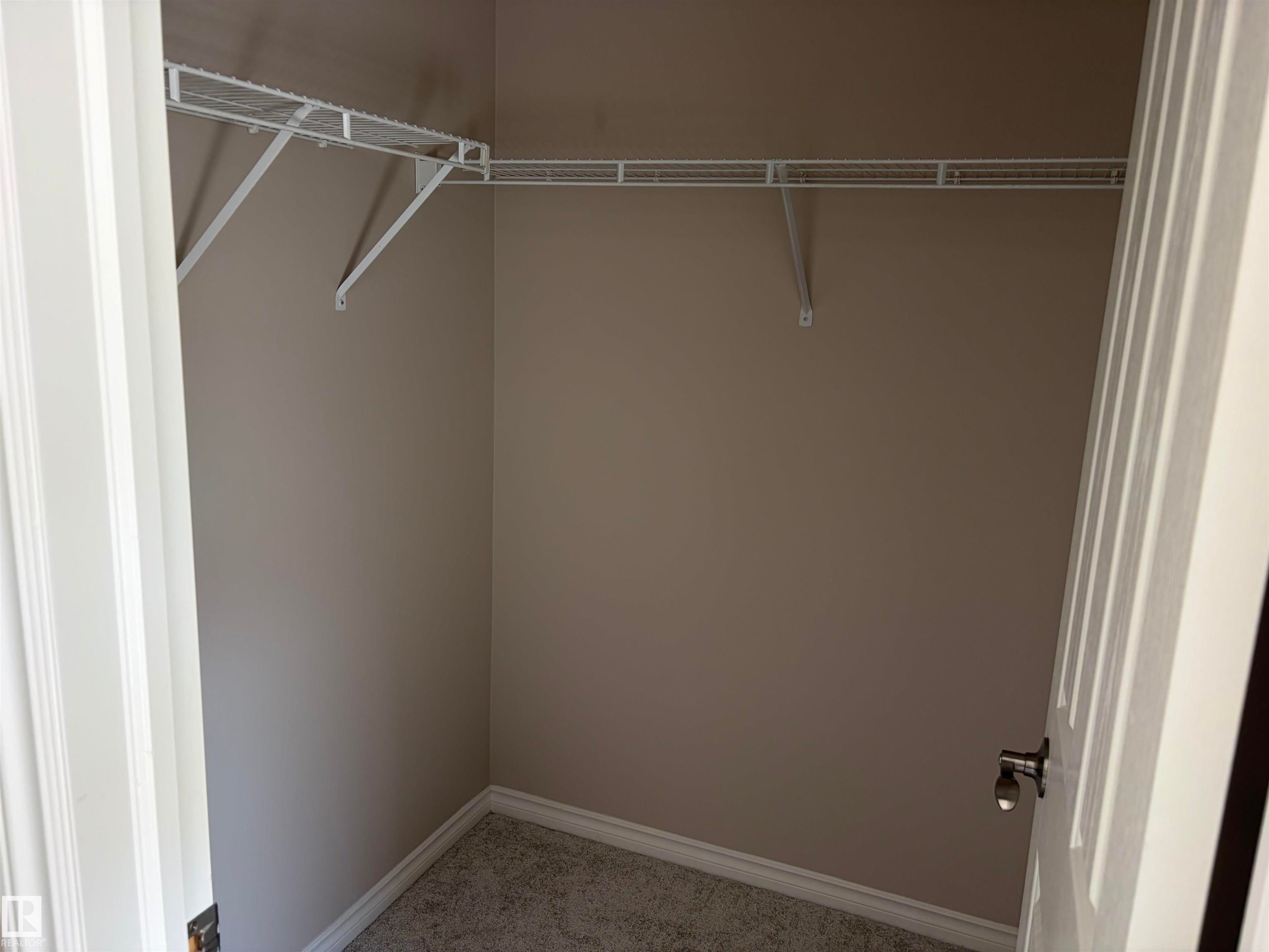 Built-in wire shelving, neutral wall paint, and gray carpeted flooring - #100 13825 155 Av Nw, Edmonton, AB