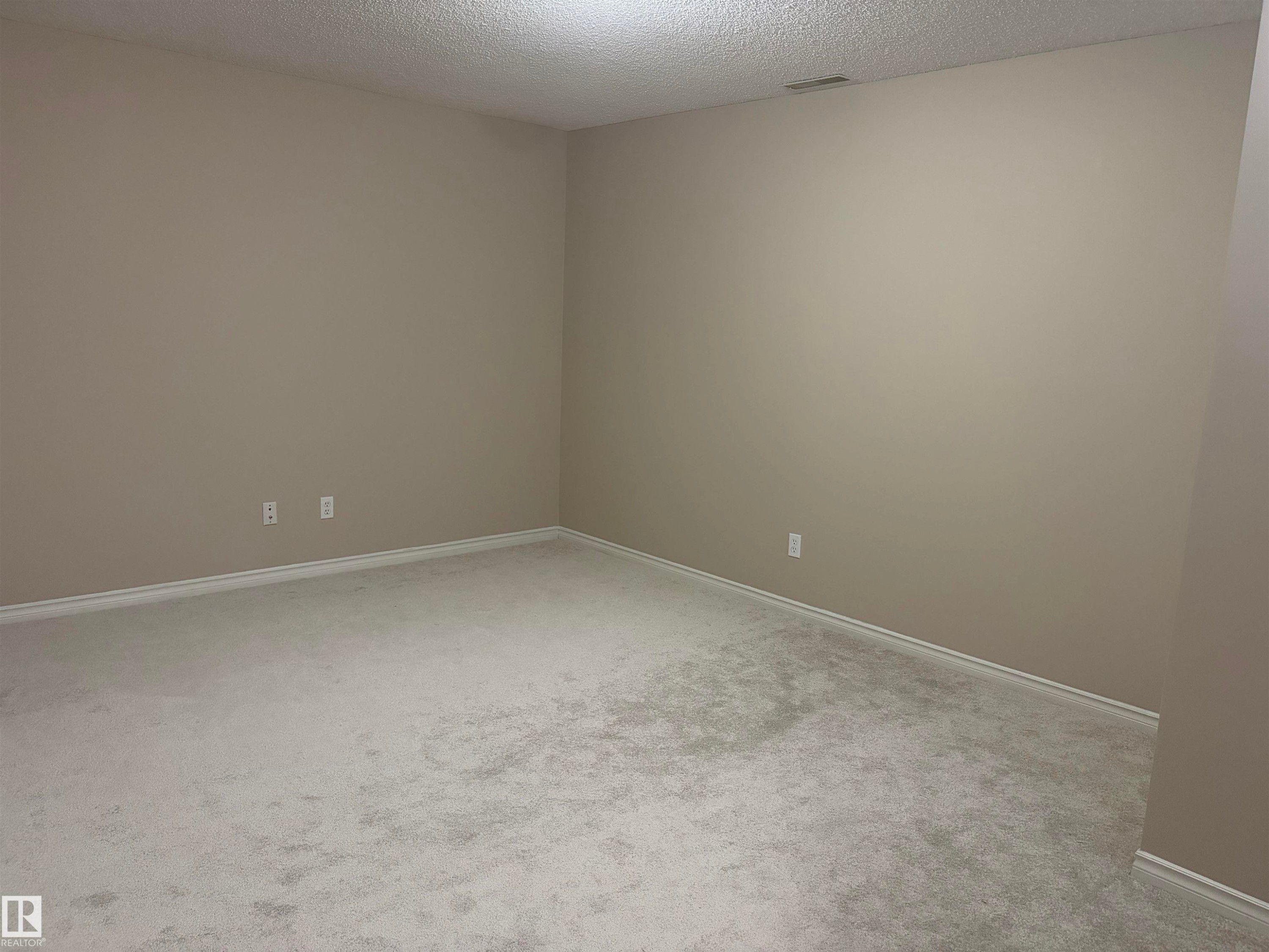 Neutral wall paint, textured ceiling, and light-colored carpeting - #100 13825 155 Av Nw, Edmonton, AB