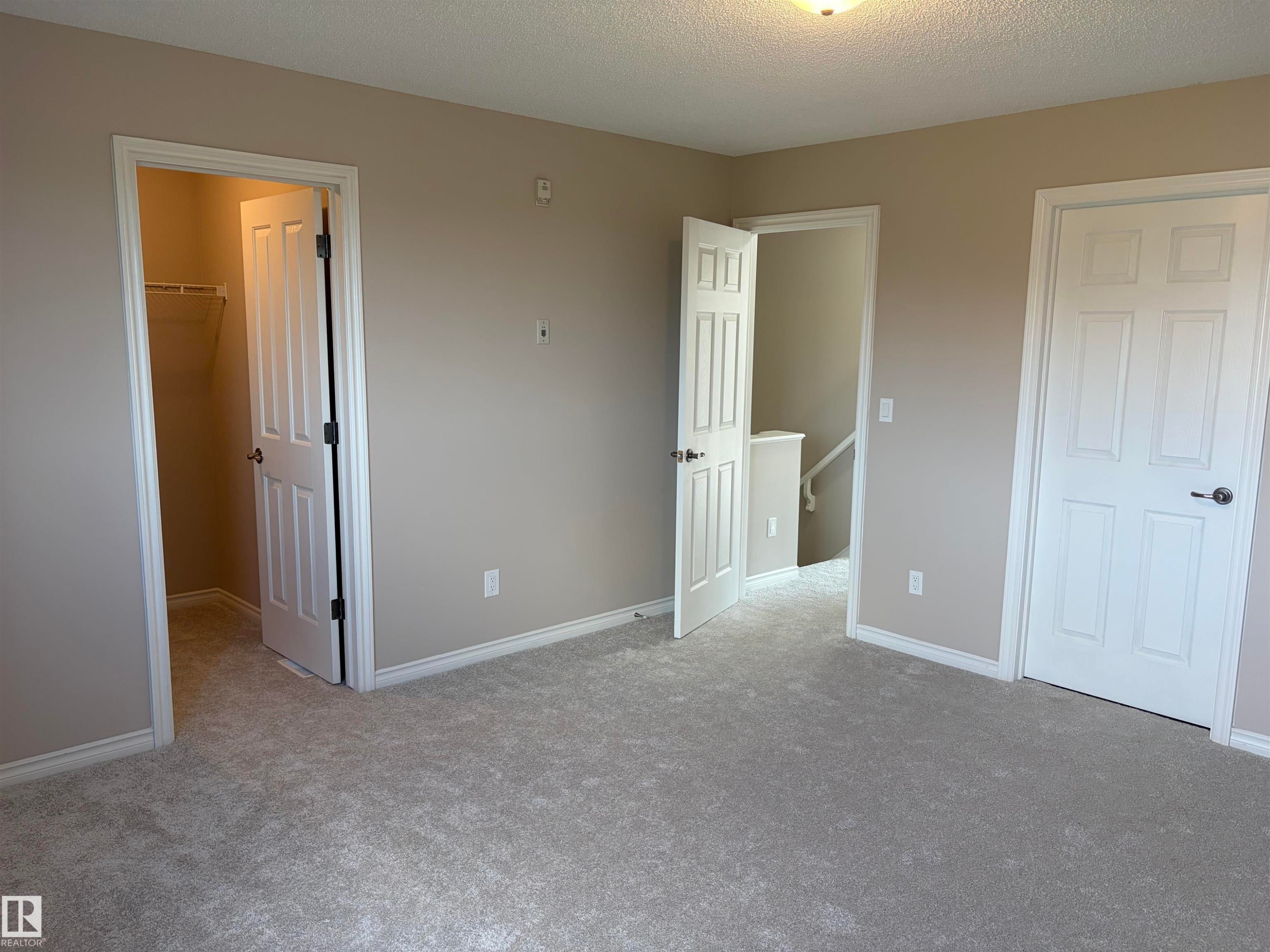 Plush carpet flooring, neutral wall color, white trim, paneled interior doors, and a ceiling-mounted light fixture - #100 13825 155 Av Nw, Edmonton, AB