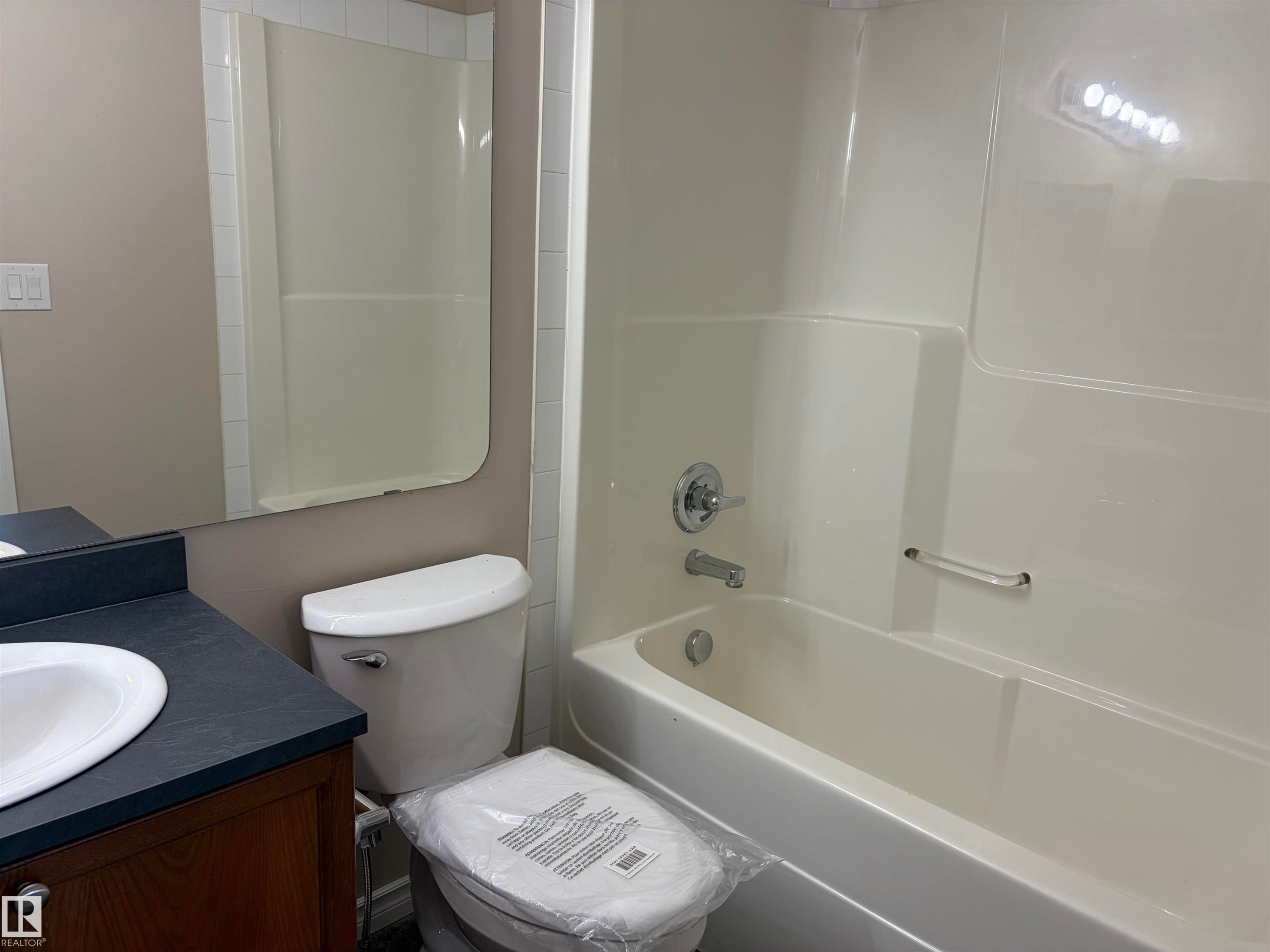 Tub and shower combination with chrome fixtures and grab bar - #100 13825 155 Av Nw, Edmonton, AB