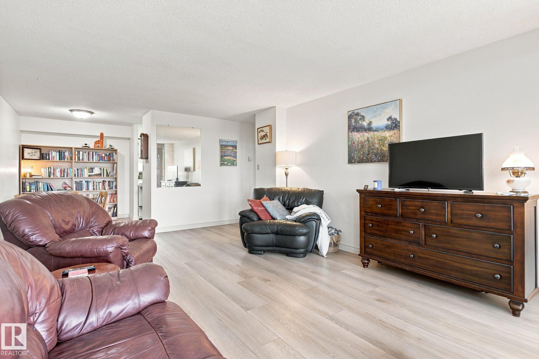 Light wood-finish flooring complements the neutral wall color - #1507 9835 113 St Nw, Edmonton, AB