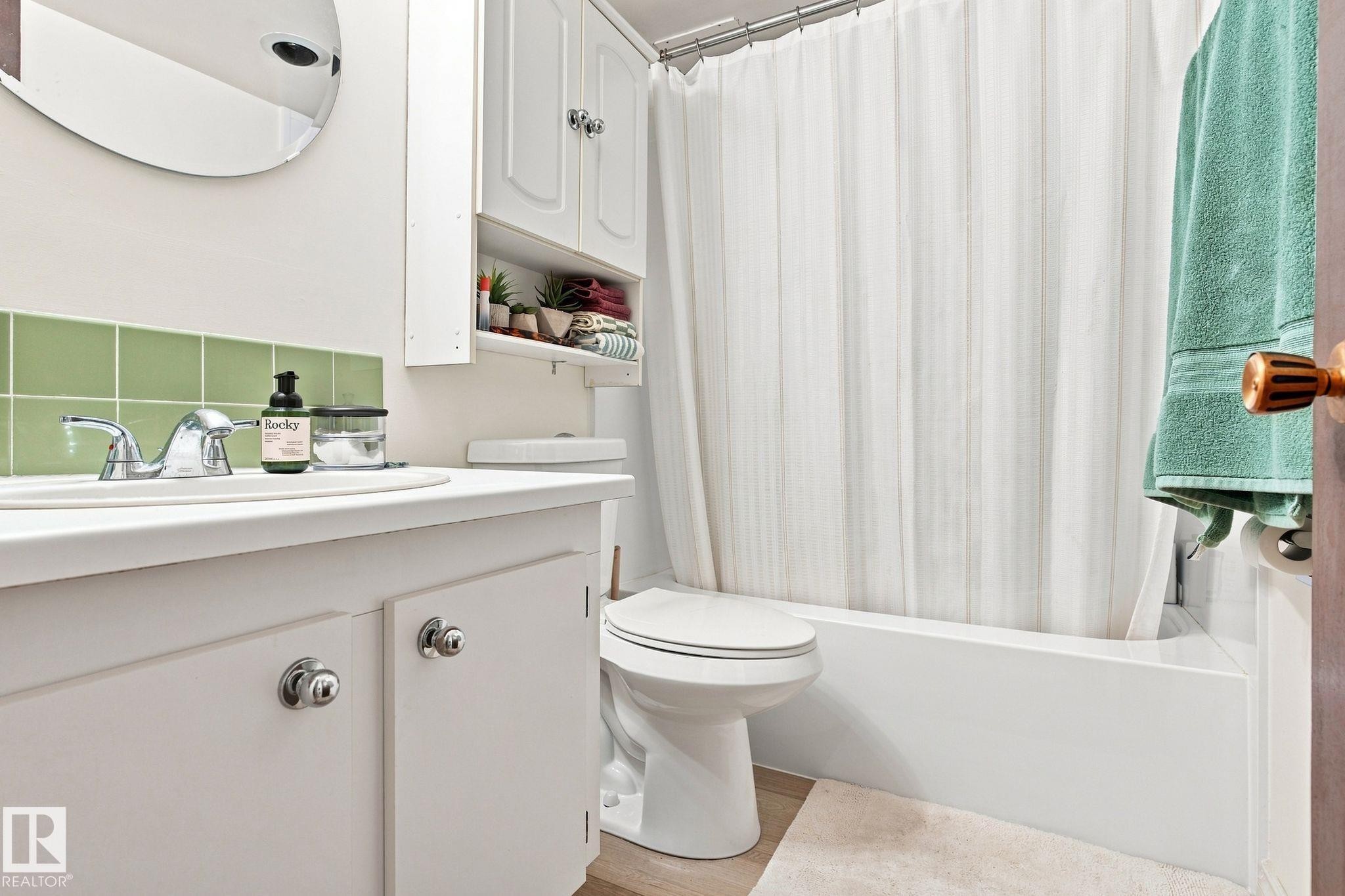 White vanity with chrome hardware, green square tile backsplash, and a white integrated sink - #1507 9835 113 St Nw, Edmonton, AB