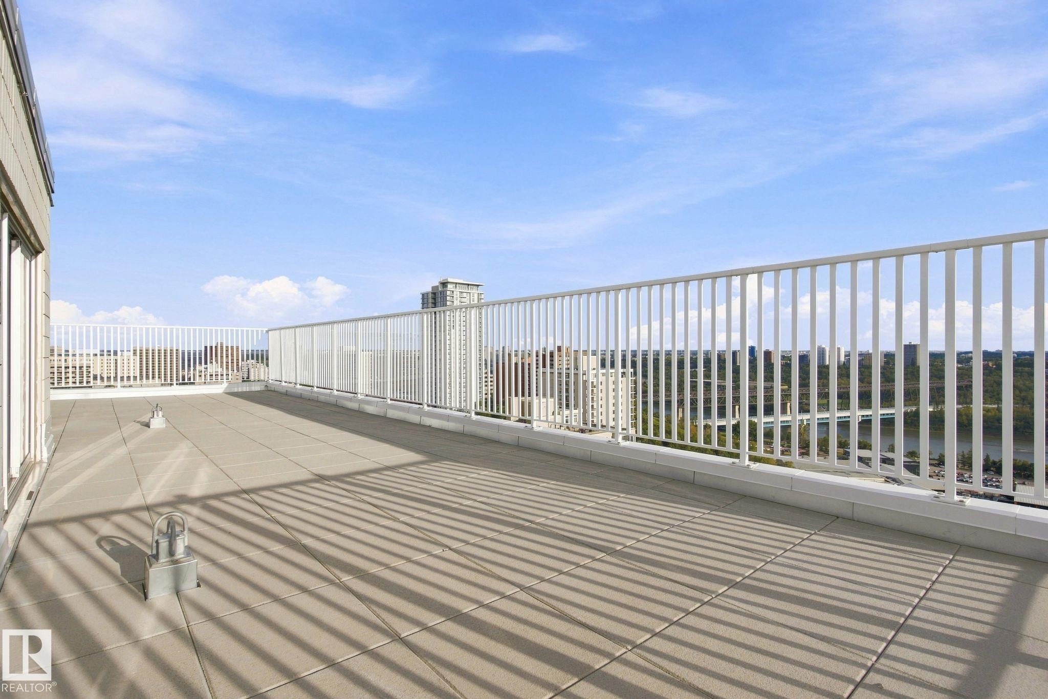 Expansive rooftop deck featuring a tiled surface and white perimeter railing - #1507 9835 113 St Nw, Edmonton, AB