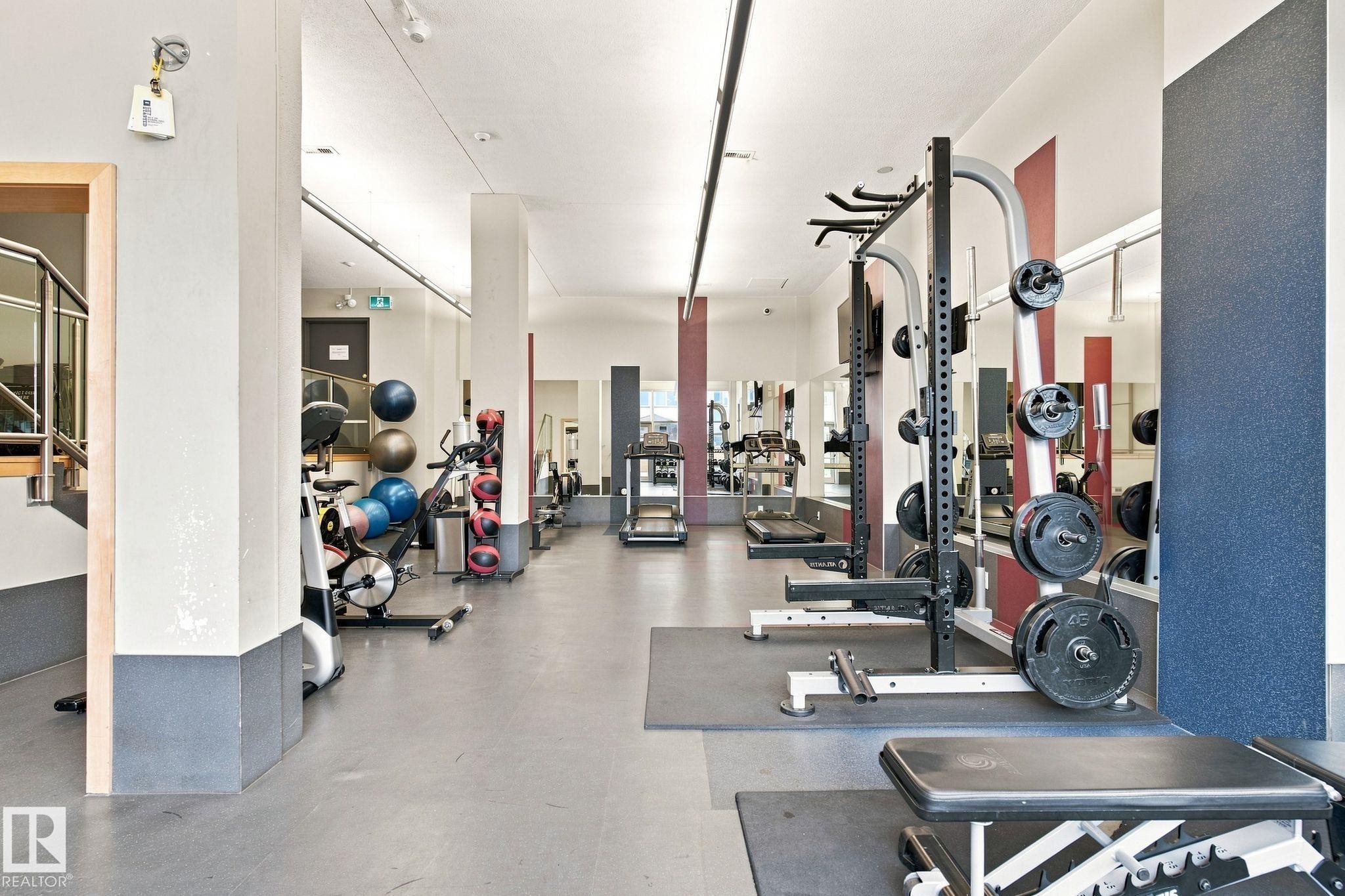 Fitness center with a selection of exercise equipment, mirrored walls, and track lighting - #1507 9835 113 St Nw, Edmonton, AB