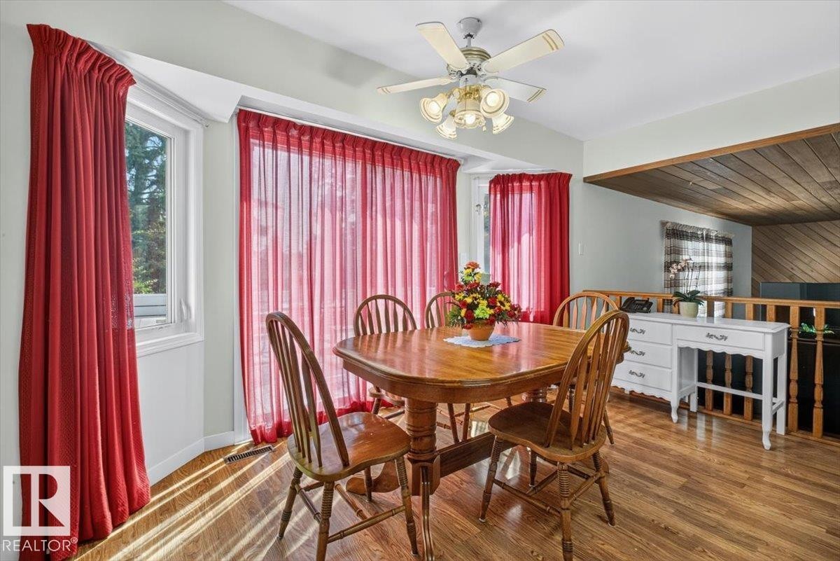 Dining area featuring wood-finish flooring, a bay window, and a ceiling fan with integrated lighting - 4027 74 Street Nw, Edmonton, AB - Indoor Photo Showing Dining Room