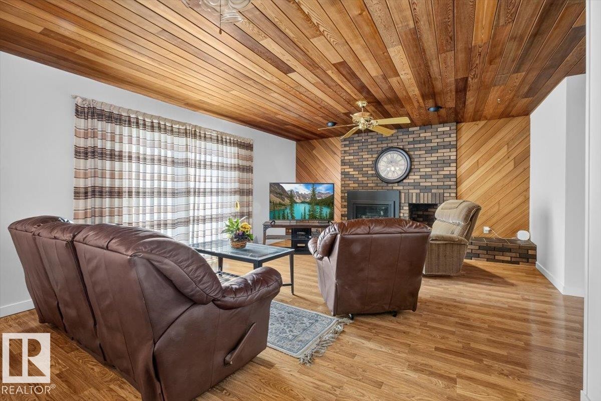 Living area featuring wood-finish flooring and a wood-paneled ceiling - 4027 74 Street Nw, Edmonton, AB - Indoor With Fireplace