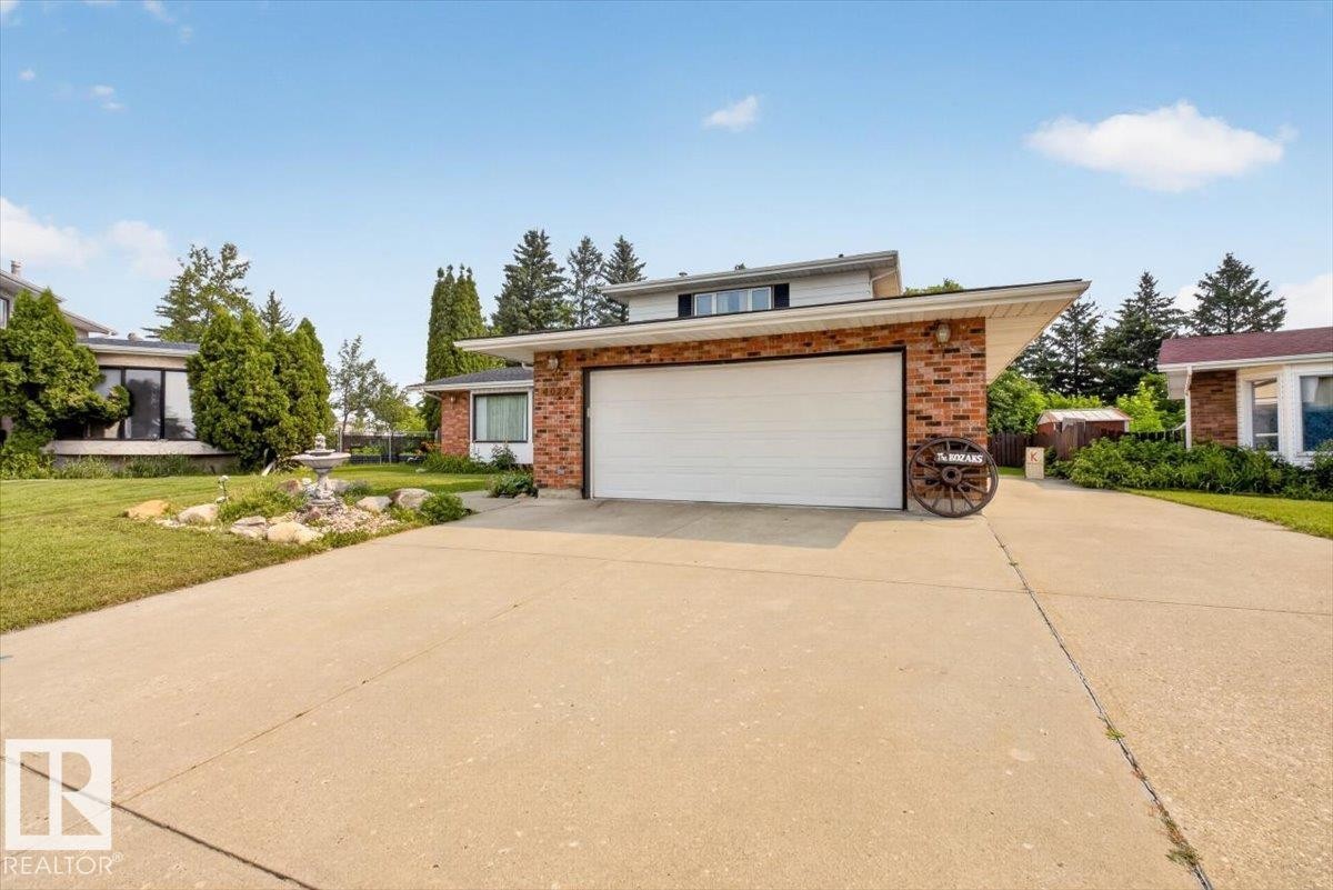 Brick facade residence featuring a two-car garage, concrete driveway, and mature landscaping - 4027 74 Street Nw, Edmonton, AB - Outdoor
