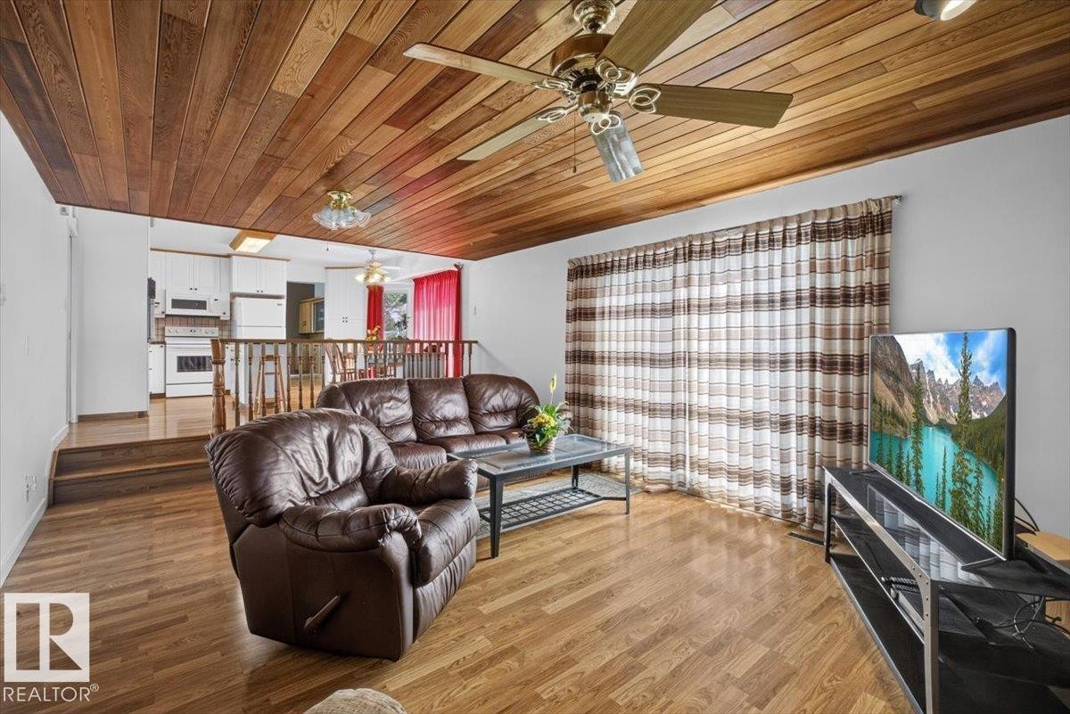 Living area featuring wood-finish flooring, a wood plank ceiling, and a ceiling fan with integrated lighting - 4027 74 Street Nw, Edmonton, AB - Indoor