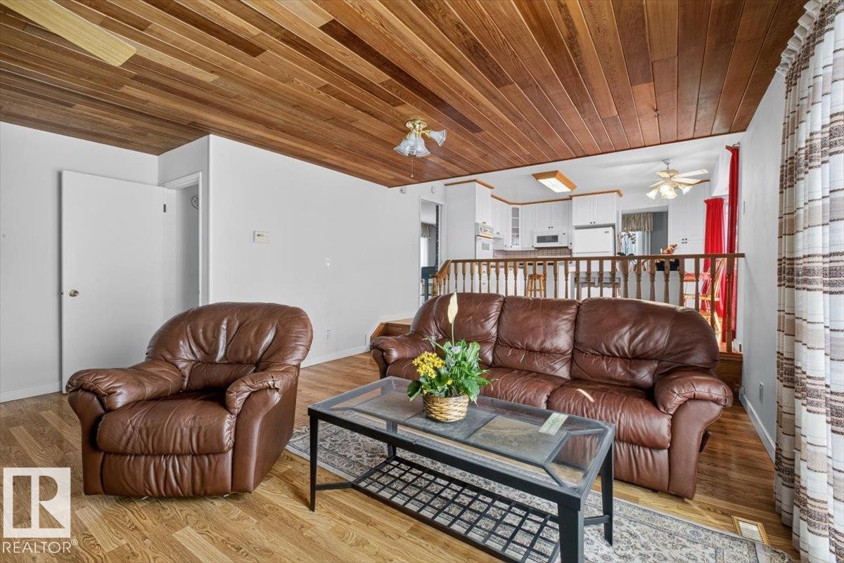 Wood-paneled ceiling accenting an open living area with wood-finish flooring - 4027 74 Street Nw, Edmonton, AB - Indoor Photo Showing Living Room