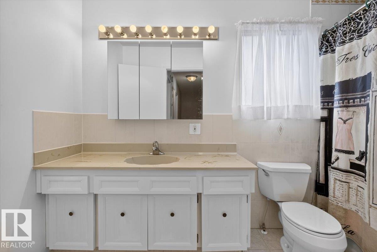 Bathroom featuring a white vanity with integrated sink, light-colored countertop, and chrome faucet - 4027 74 Street Nw, Edmonton, AB - Indoor Photo Showing Bathroom