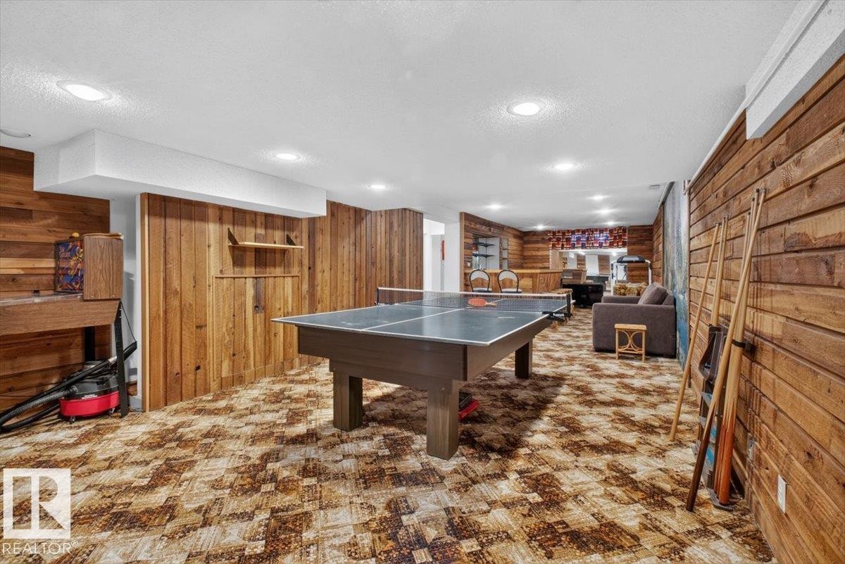 Recreational room featuring wood-paneled walls, a drop ceiling with recessed lighting, and patterned carpet flooring - 4027 74 Street Nw, Edmonton, AB - Indoor Photo Showing Other Room