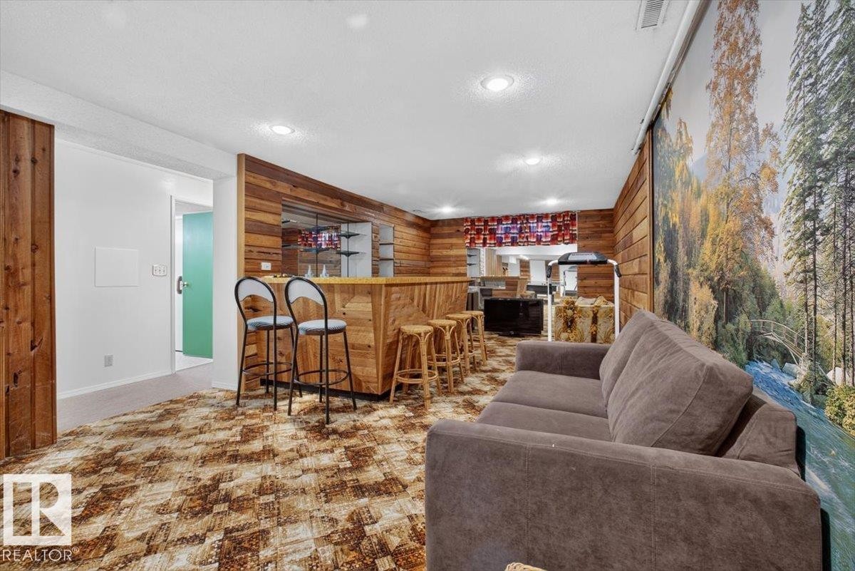 Recreation room featuring a built-in bar with wood-finish paneling, patterned carpet, and recessed lighting - 4027 74 Street Nw, Edmonton, AB - Indoor Photo Showing Living Room