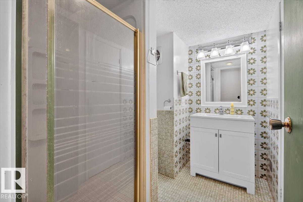 Bathroom featuring a white vanity with a single sink, an overhead four-bulb light fixture, and a framed mirror - 4027 74 Street Nw, Edmonton, AB - Indoor Photo Showing Bathroom