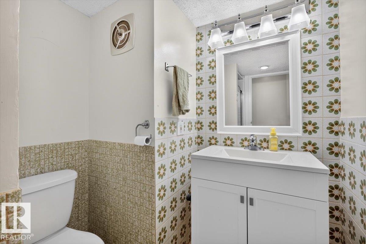 Bathroom featuring a white vanity with integrated sink, chrome faucet, and a wall-mounted mirror - 4027 74 Street Nw, Edmonton, AB - Indoor Photo Showing Bathroom