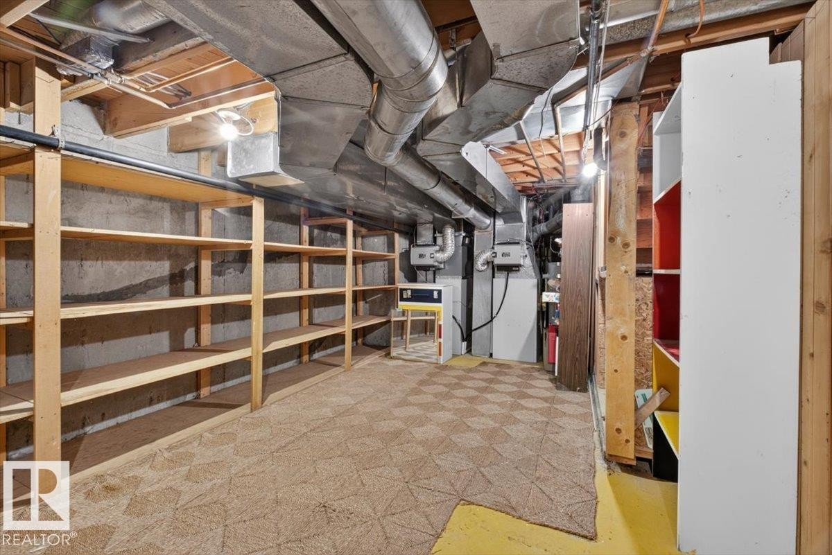 Basement storage area featuring extensive built-in shelving, concrete walls, exposed ductwork, utility access, and patterned carpet flooring - 4027 74 Street Nw, Edmonton, AB - Indoor Photo Showing Basement